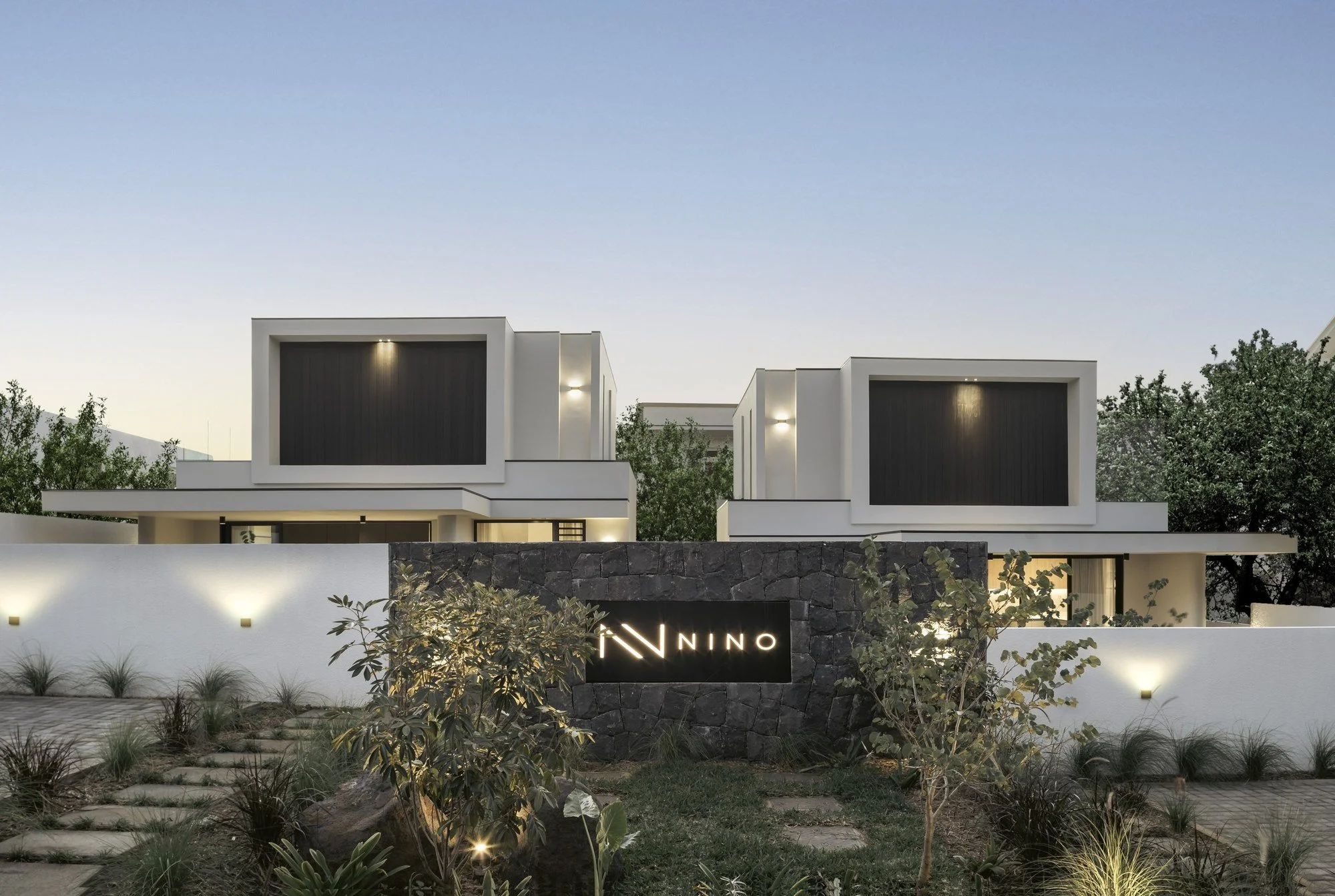 Façade nocturne de la villa Nino, architecture contemporaine aux volumes géométriques.