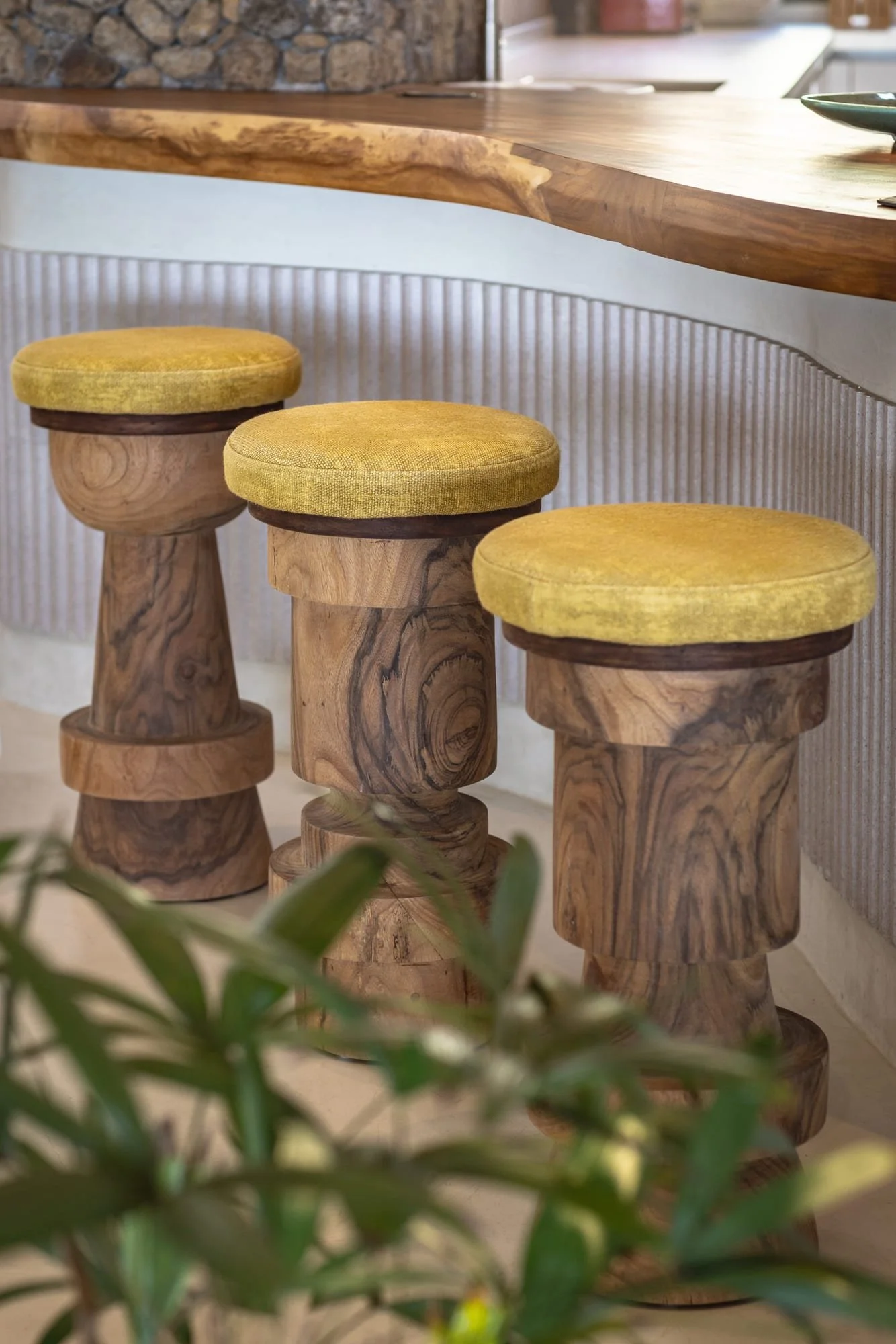 Hand-carved timber bar stools beneath a sculptural kitchen counter