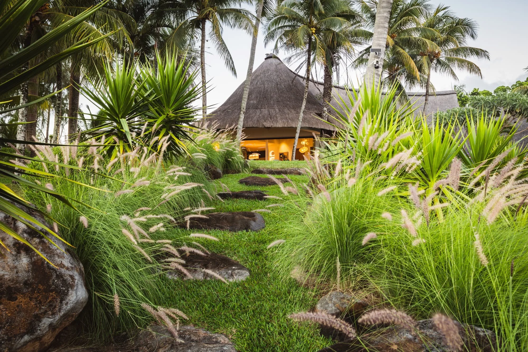 Thatched pavilion surrounded by layered tropical landscaping