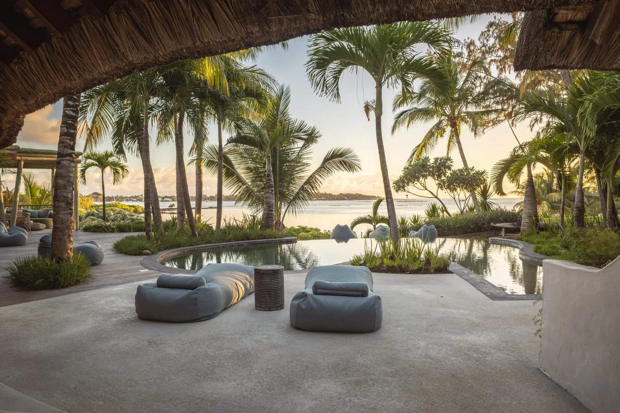 Pool terrace and outdoor lounge framed by palms in evening light