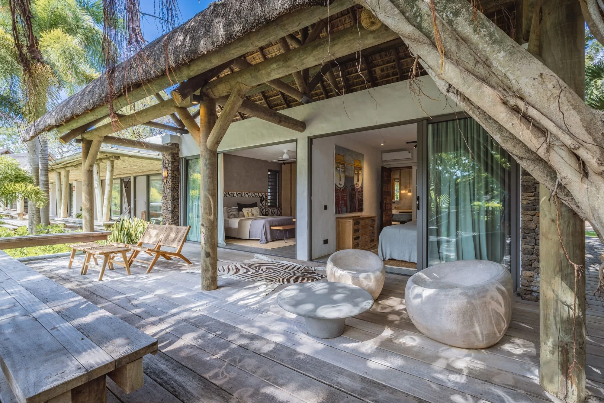Thatched bedroom pavilion nestled beneath a mature banyan tree