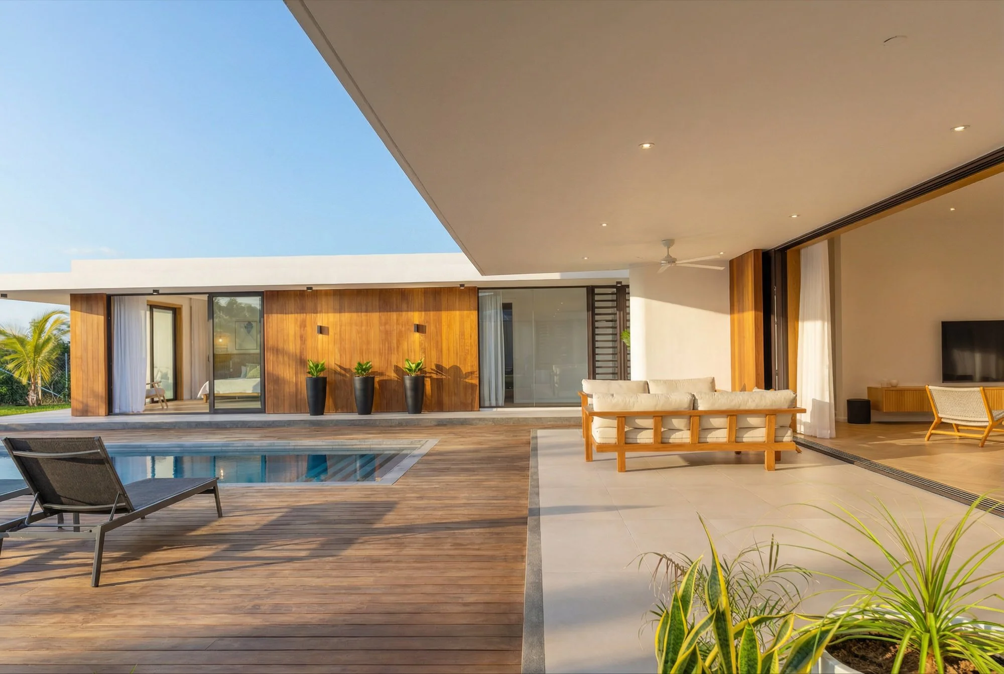 Terrasse moderne avec piscine, mobilier en bois et vue sur une maison contemporaine avec un plafond blanc et un ciel clair.