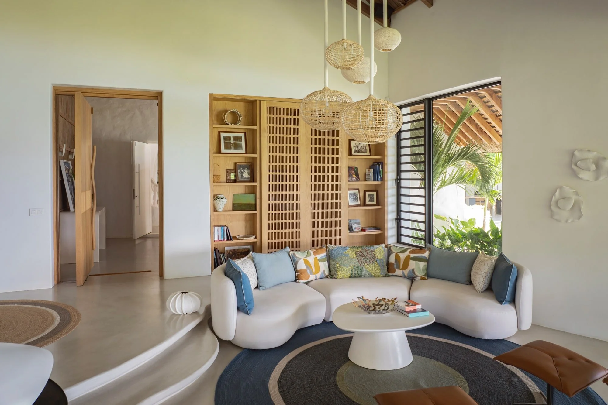 Curved living room seating with bespoke joinery and woven pendant lights