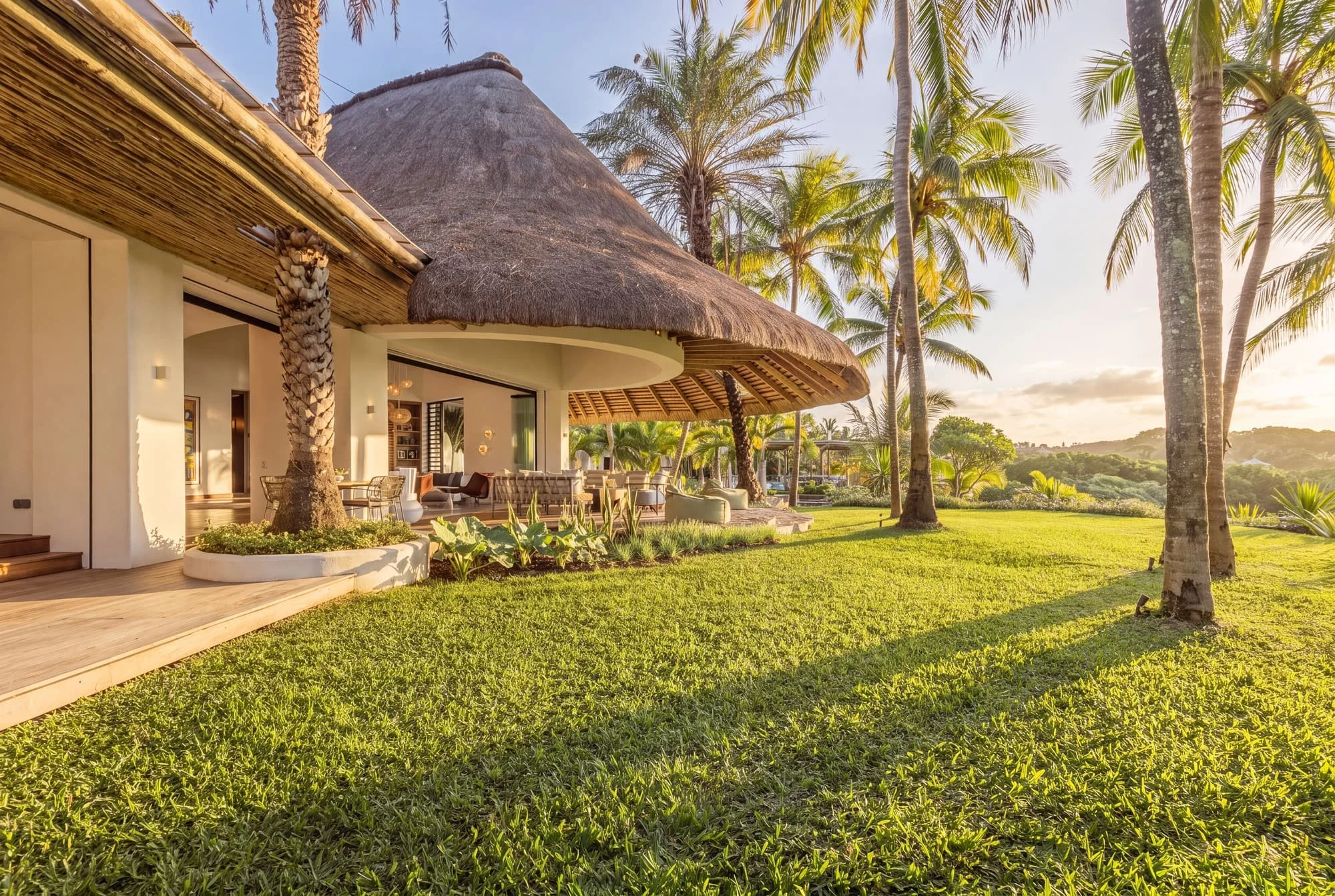 Thatched villa facade and tropical garden in warm sunset light