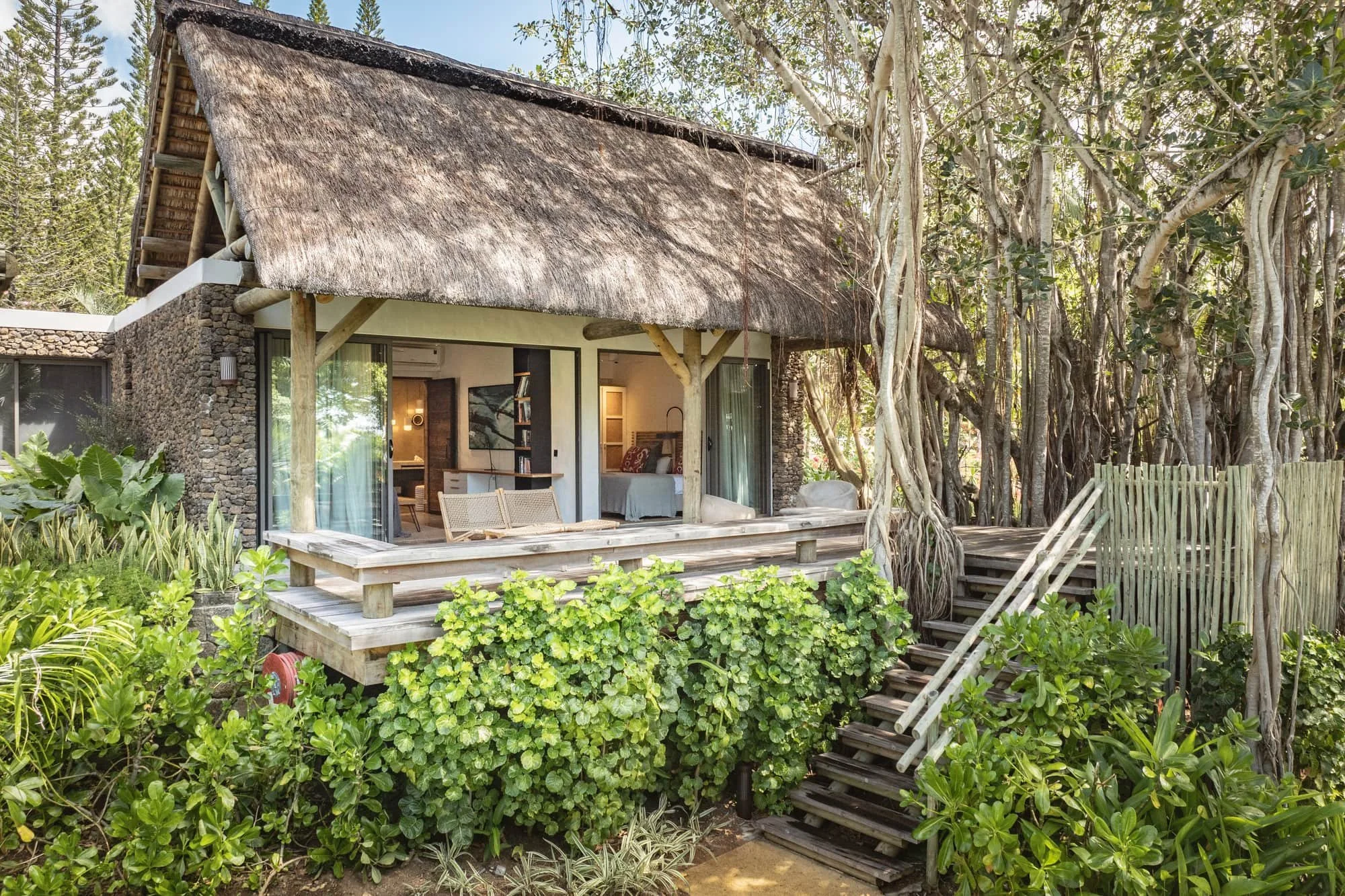 Thatched private bedroom suite surrounded by lush tropical vegetation