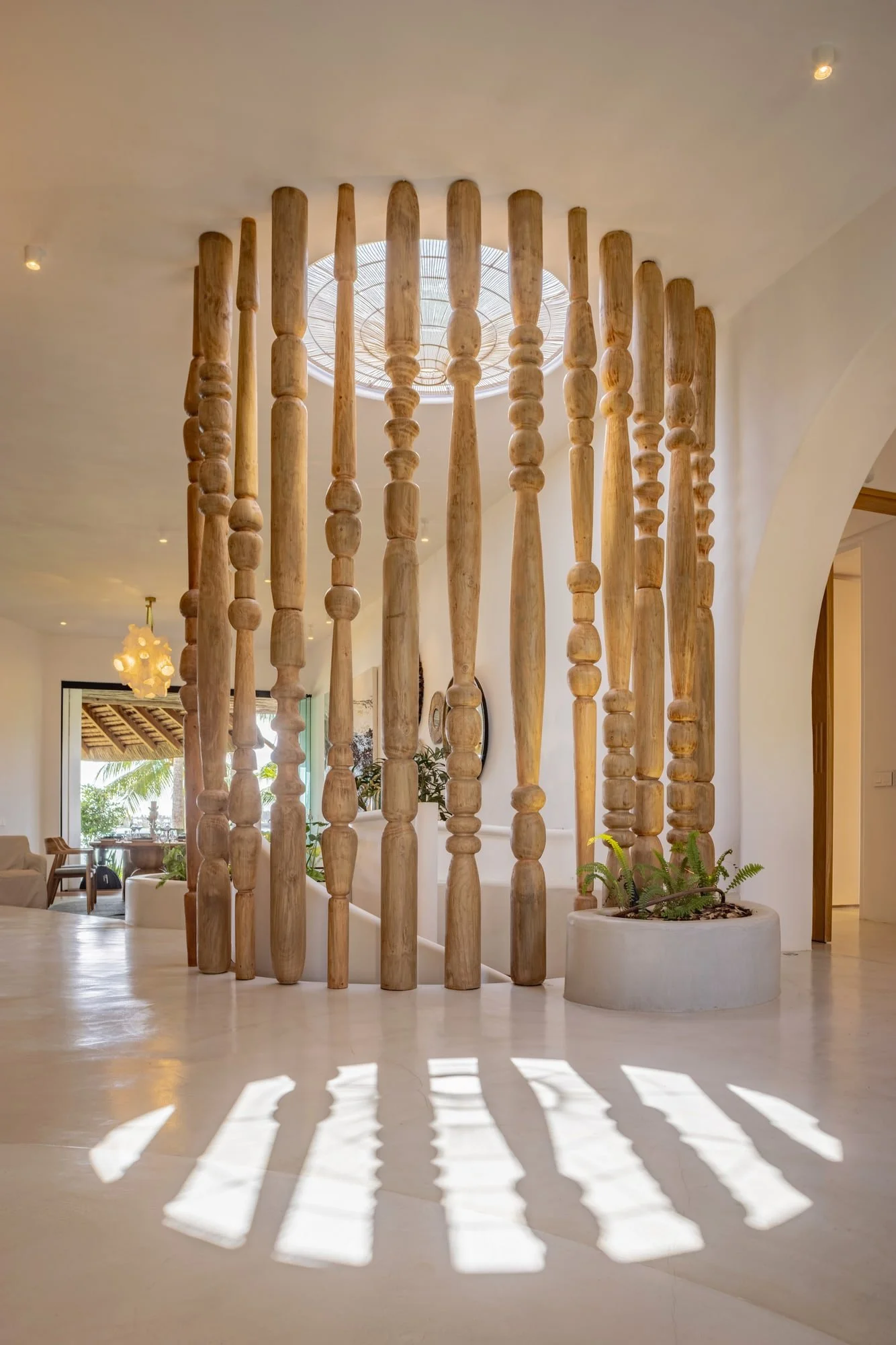 Sculptural timber screen casting patterned light across the entrance hall