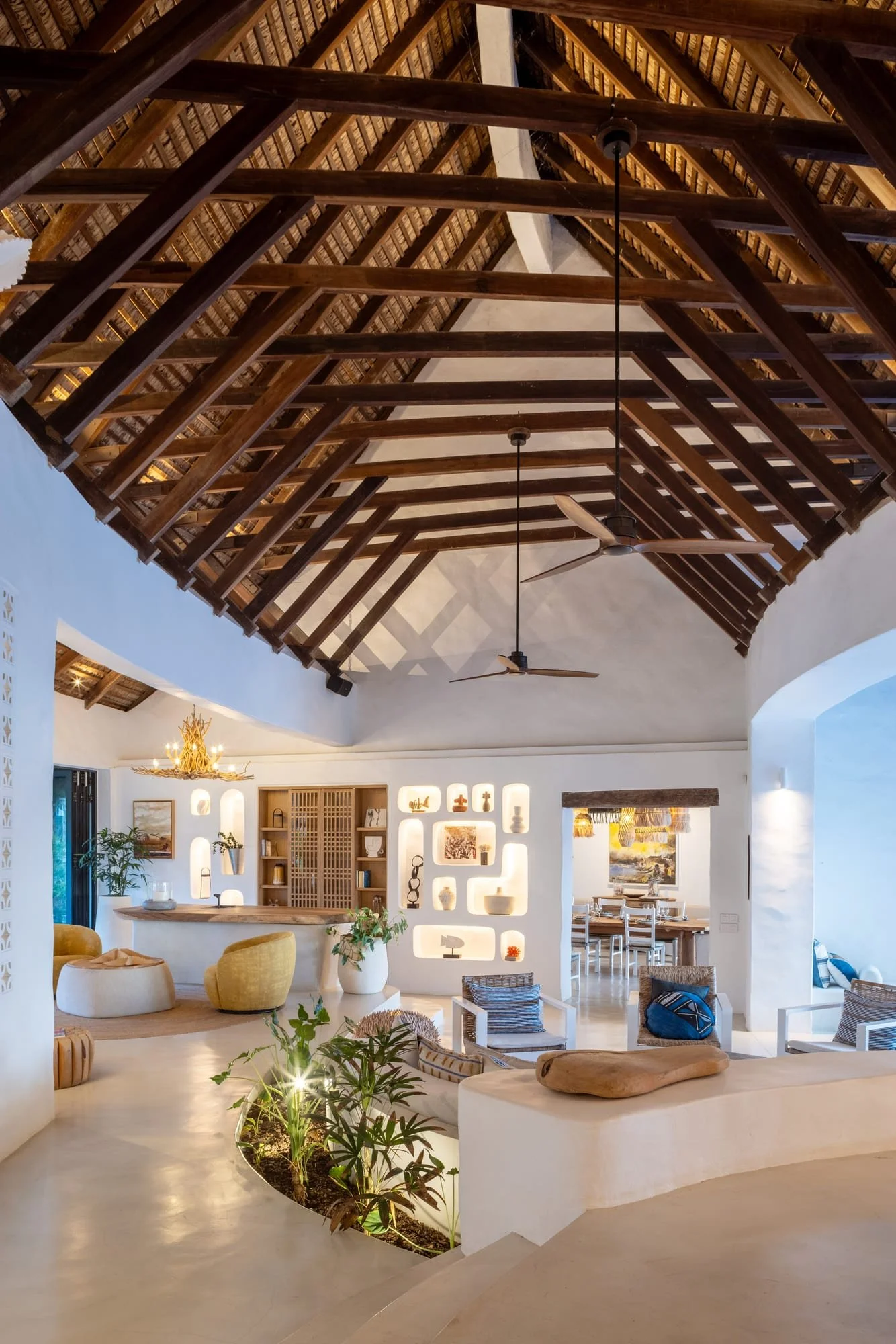 Vaulted open-plan interior with exposed timber roof and tropical planting
