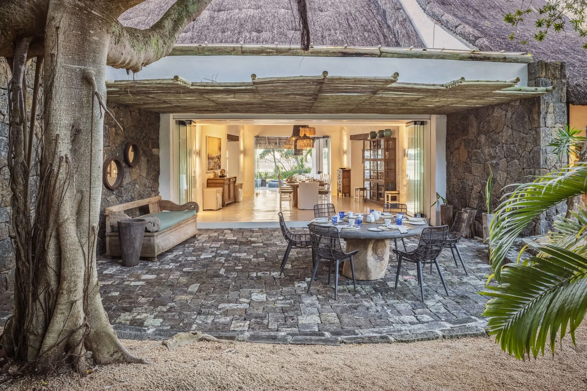 Stone courtyard dining area beneath a mature tropical tree