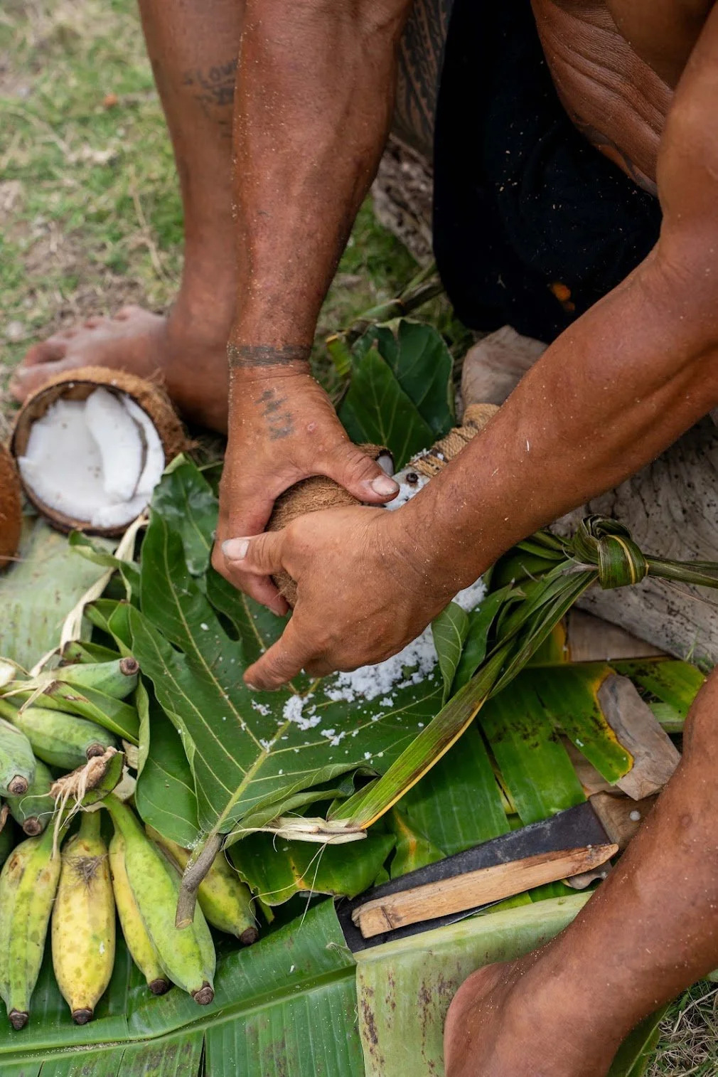 Kap's hands prepare a halved coconut.