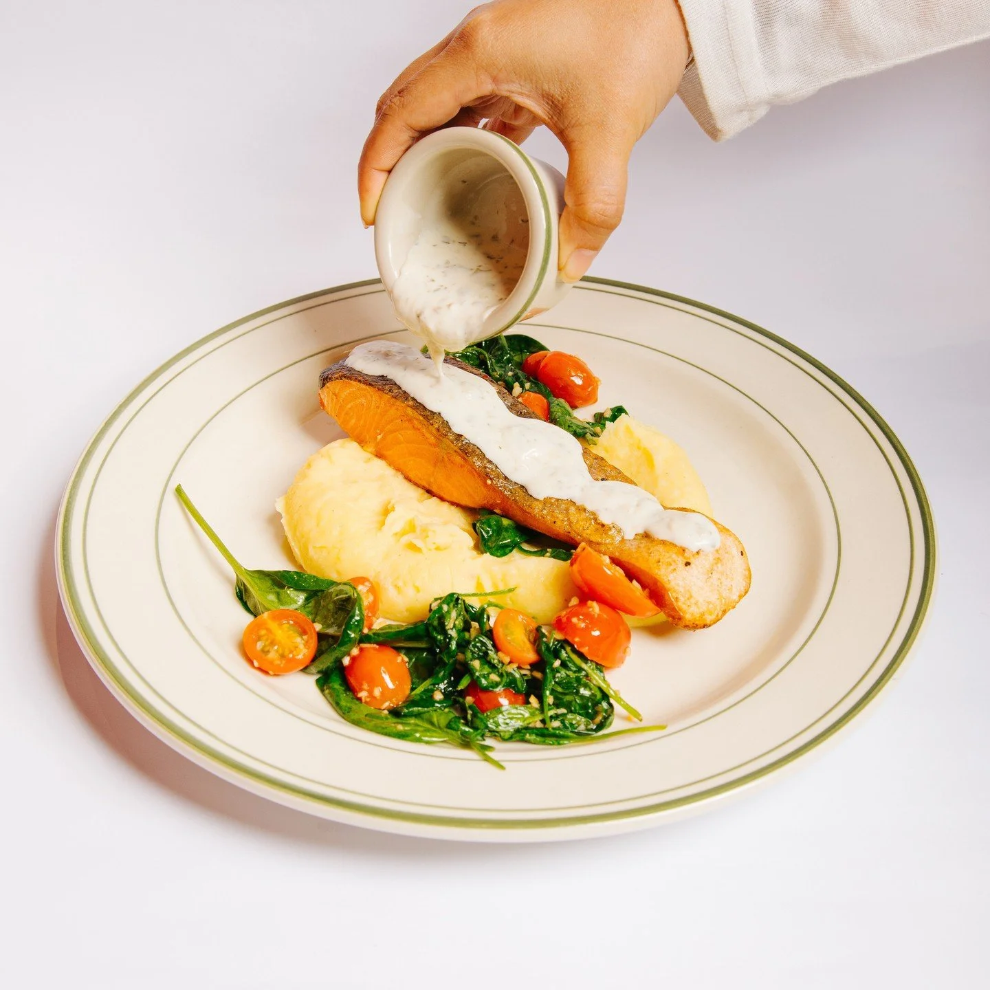 A balanced plate: crisp salmon, mash, vegetables, and caper cream.