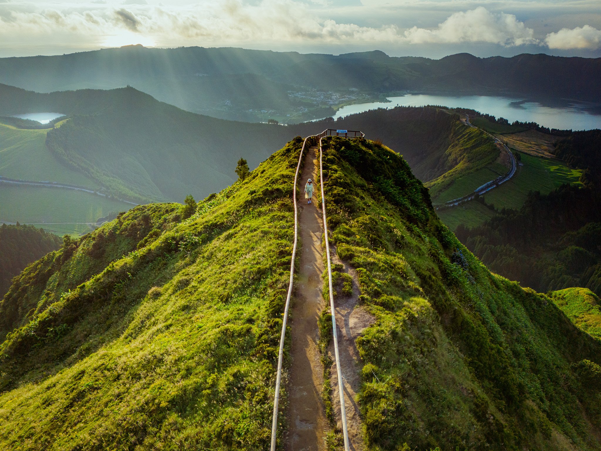Hiker walking along a scenic ridge trail overlooking volcanic lakes in Sete Cidades, São Miguel, Azores, during a private tour focused on nature, viewpoints, and hidden gems