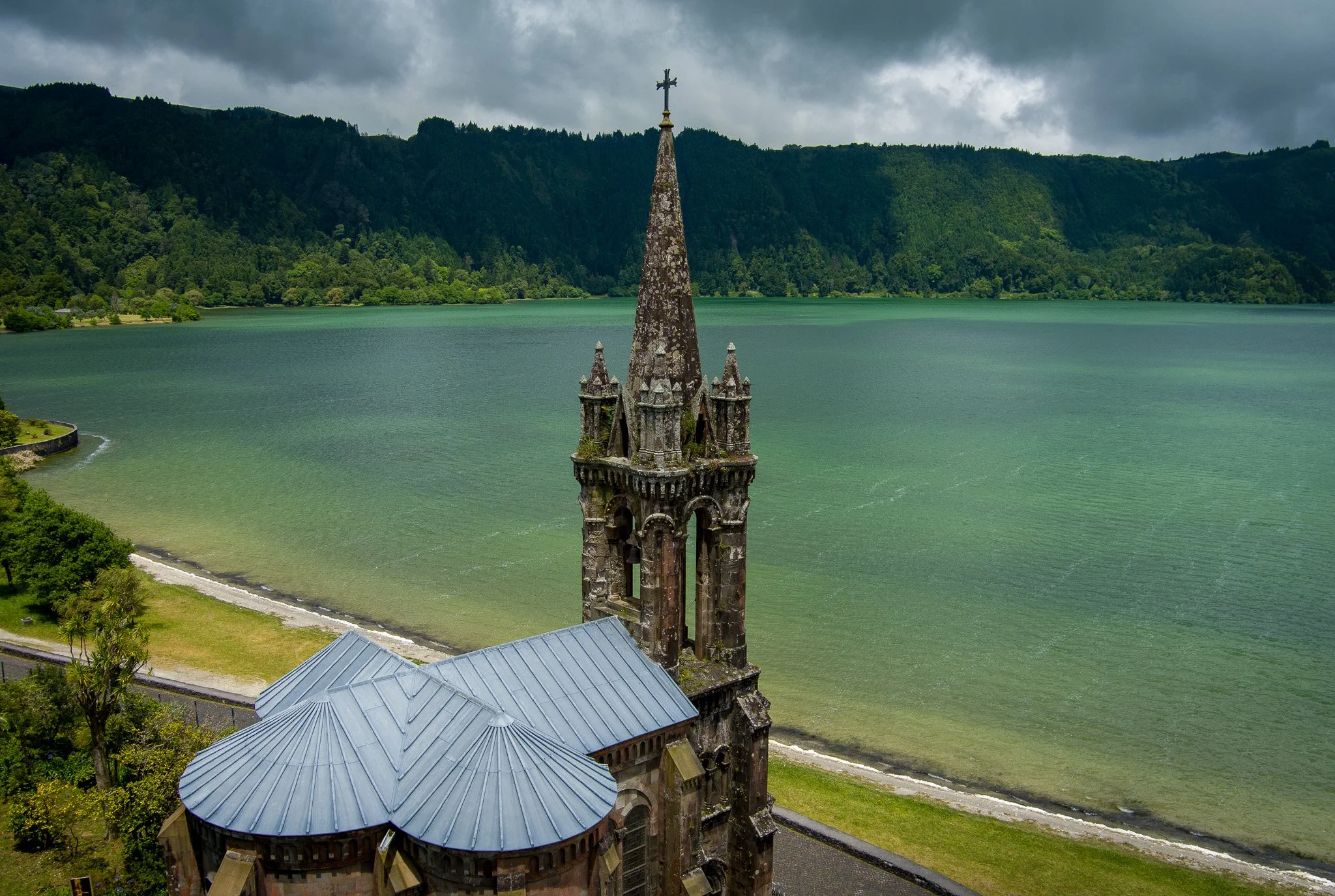 View of the church tower and Furnas Lake surrounded by green volcanic hills in São Miguel, Azores