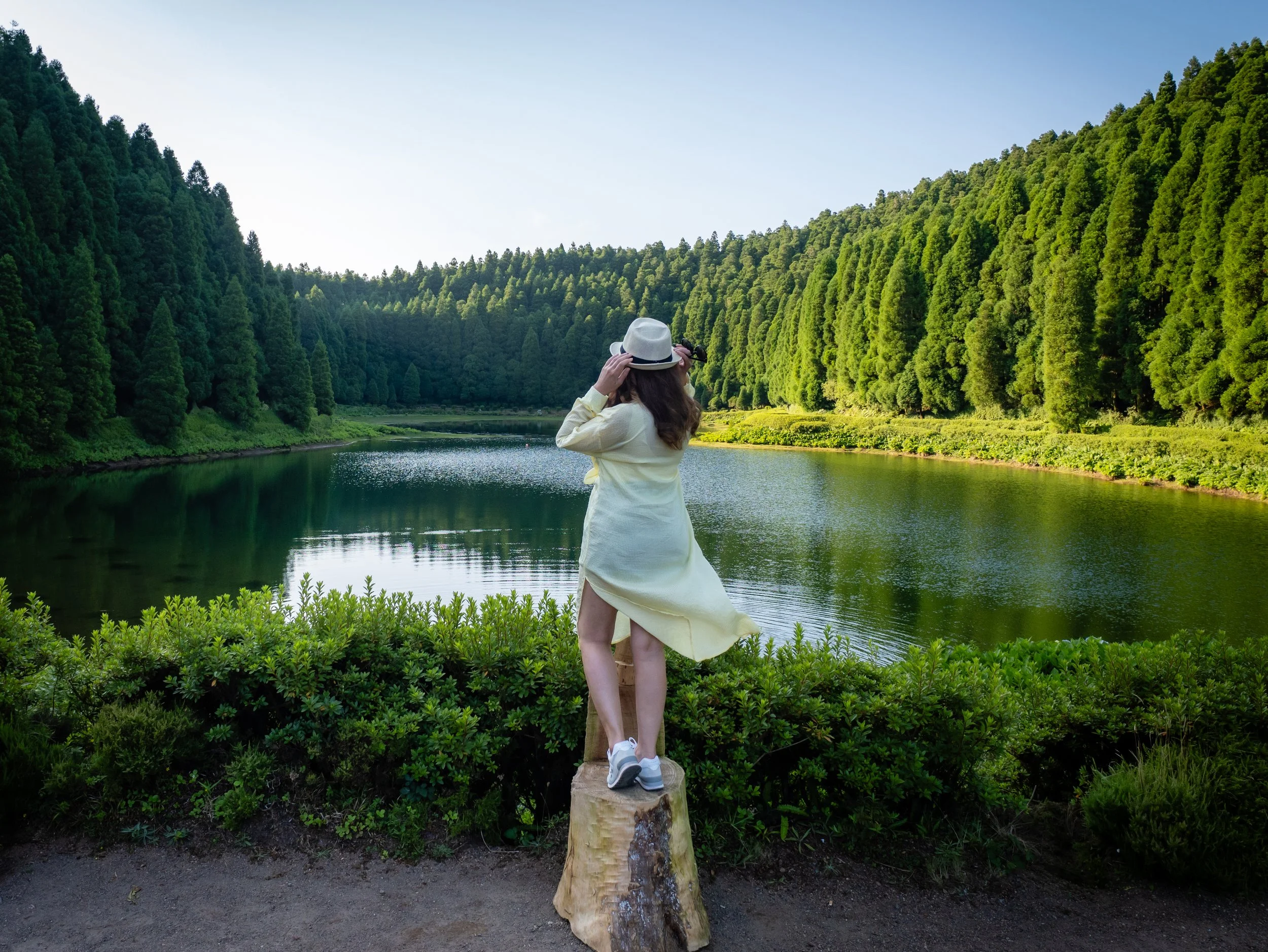Woman admiring a peaceful lake surrounded by forest in São Miguel, Azores during a cruise stop