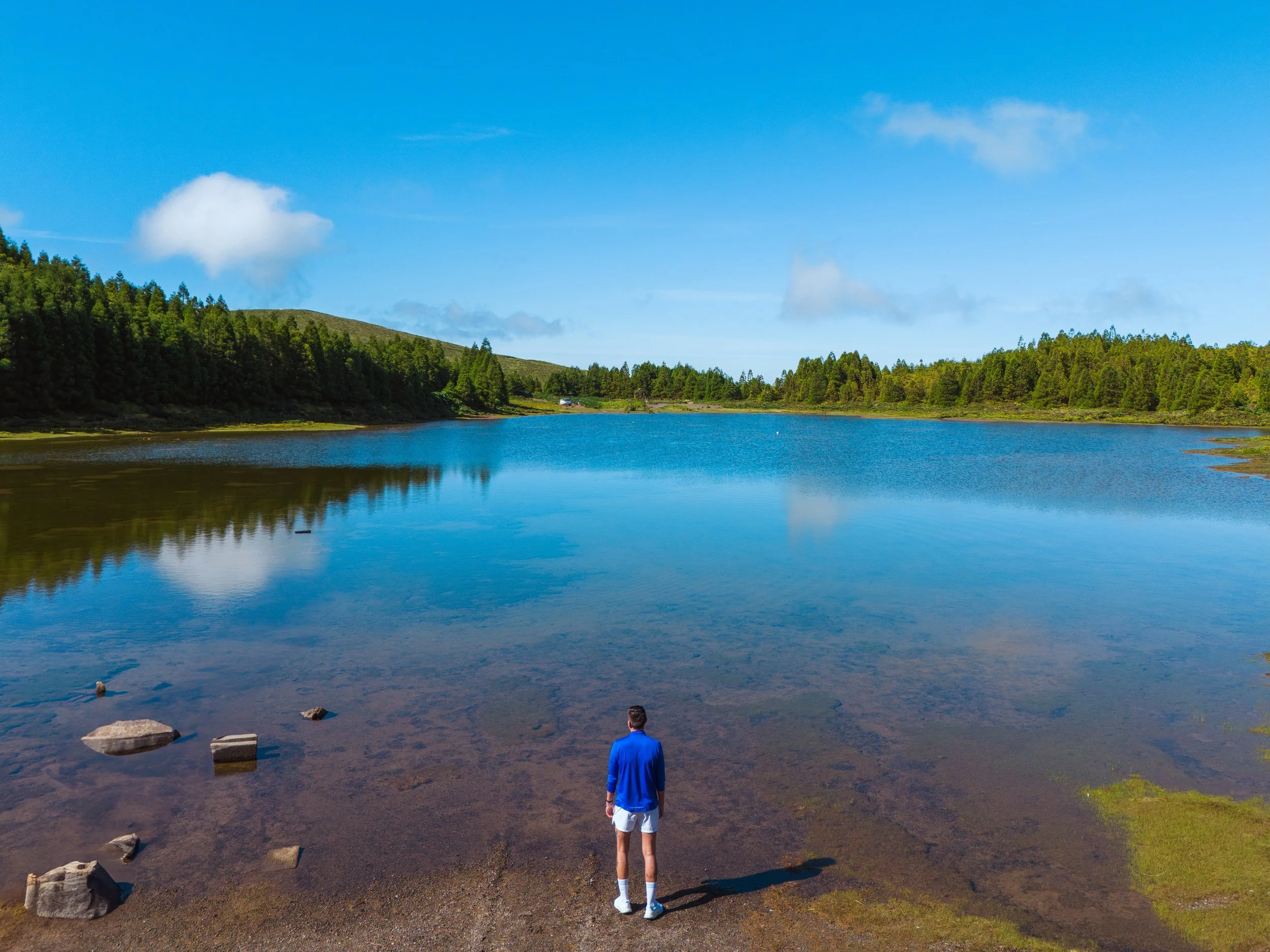 A man standing by a serene lake during an Azores travel experience, perfect for a landscape photoshoot with a professional São Miguel photographer