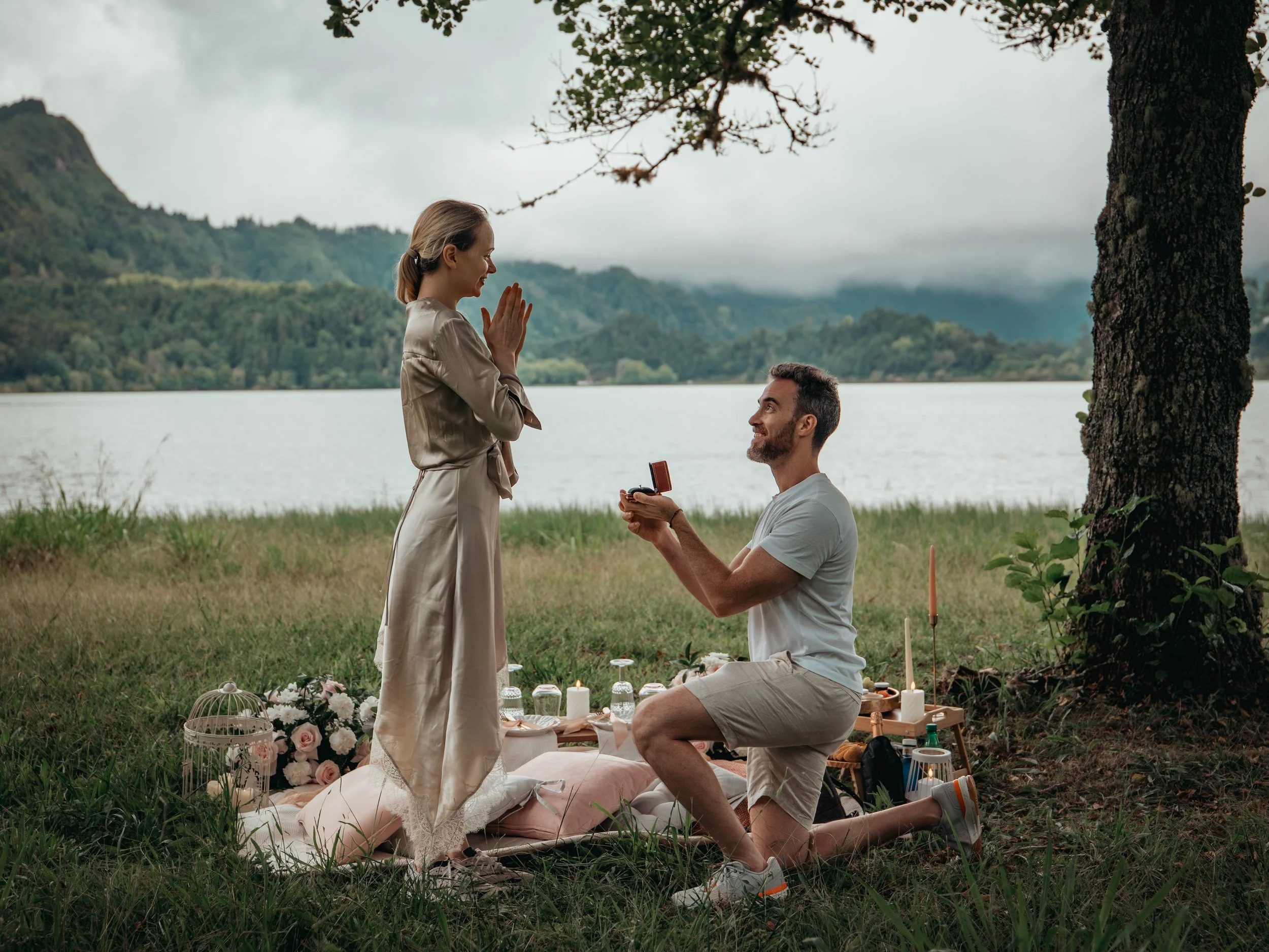 Surprise marriage proposal by a lake in São Miguel, Azores, with a couple during a romantic picnic setup