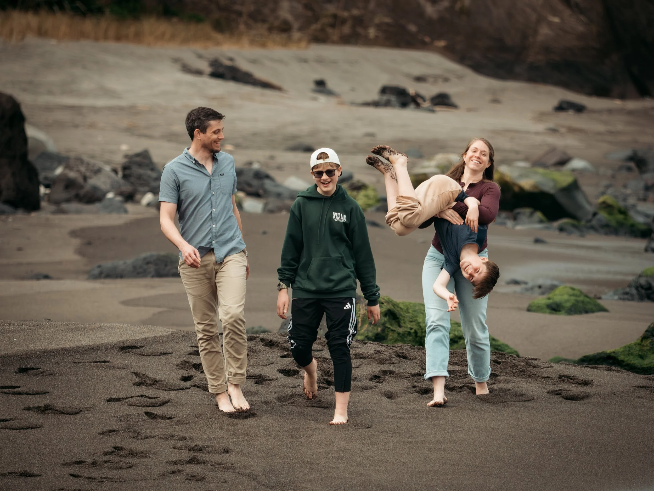 Family walking on a black sand beach in São Miguel, Azores, during a relaxed private photo tour with an Azores photographer