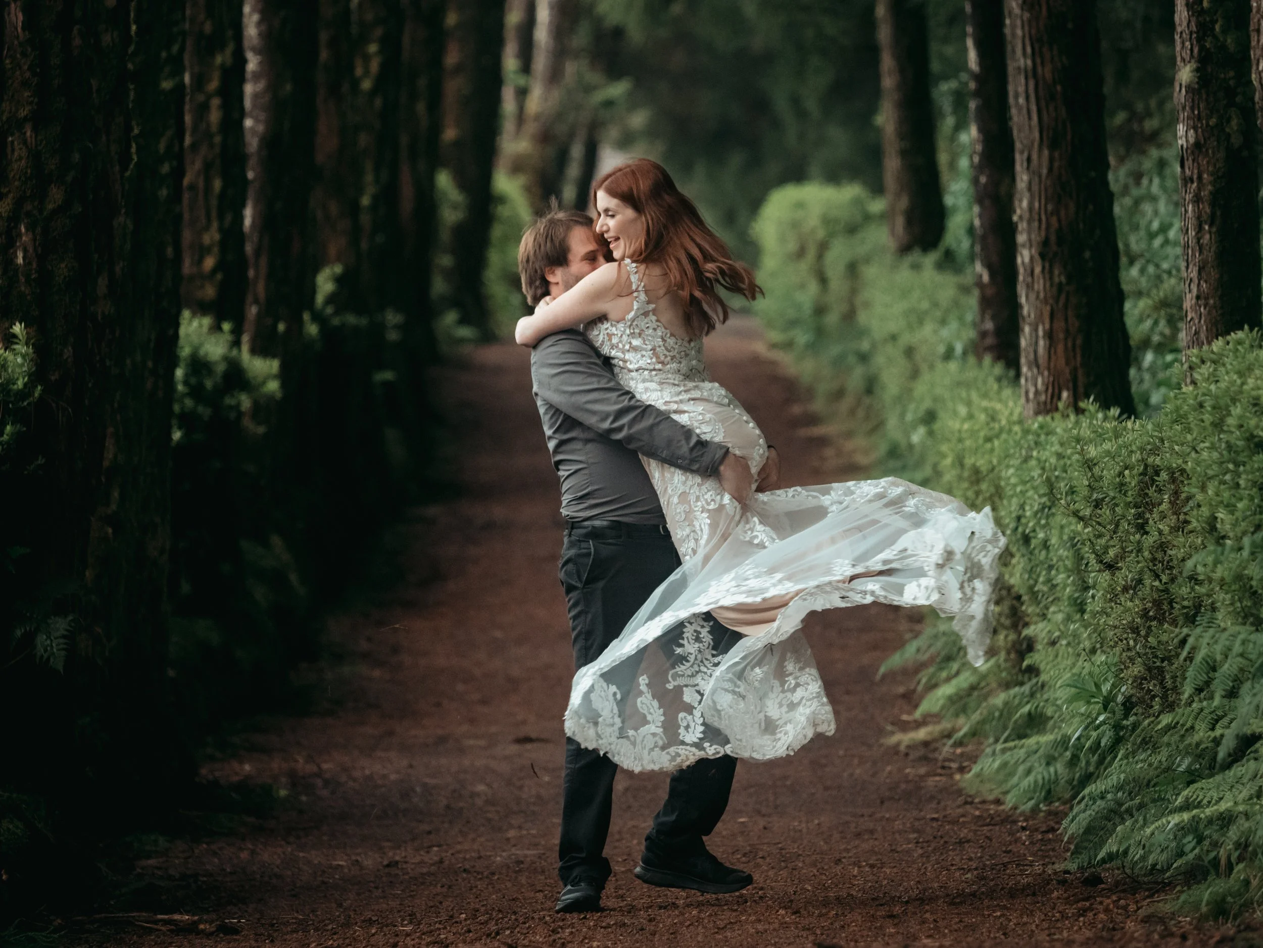 Couple enjoying an intimate moment during a private photo tour in a forest trail in São Miguel, Azores, captured naturally by a local photographer during a personalized experience.