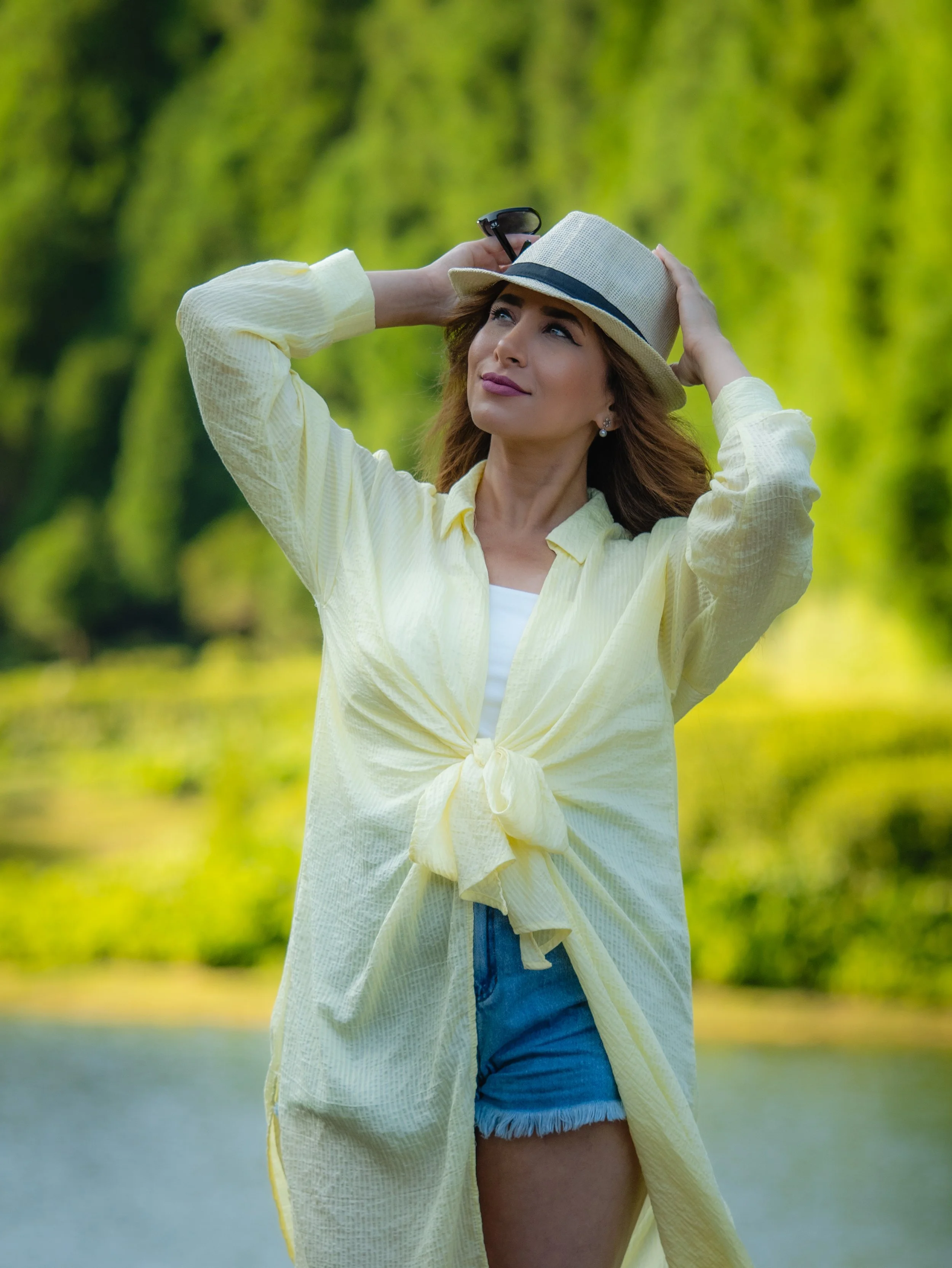A stunning beauty portrait from an Azores travel photoshoot featuring a woman in a straw hat and yellow outfit, captured by a professional Azores photographer in a lush green natural setting