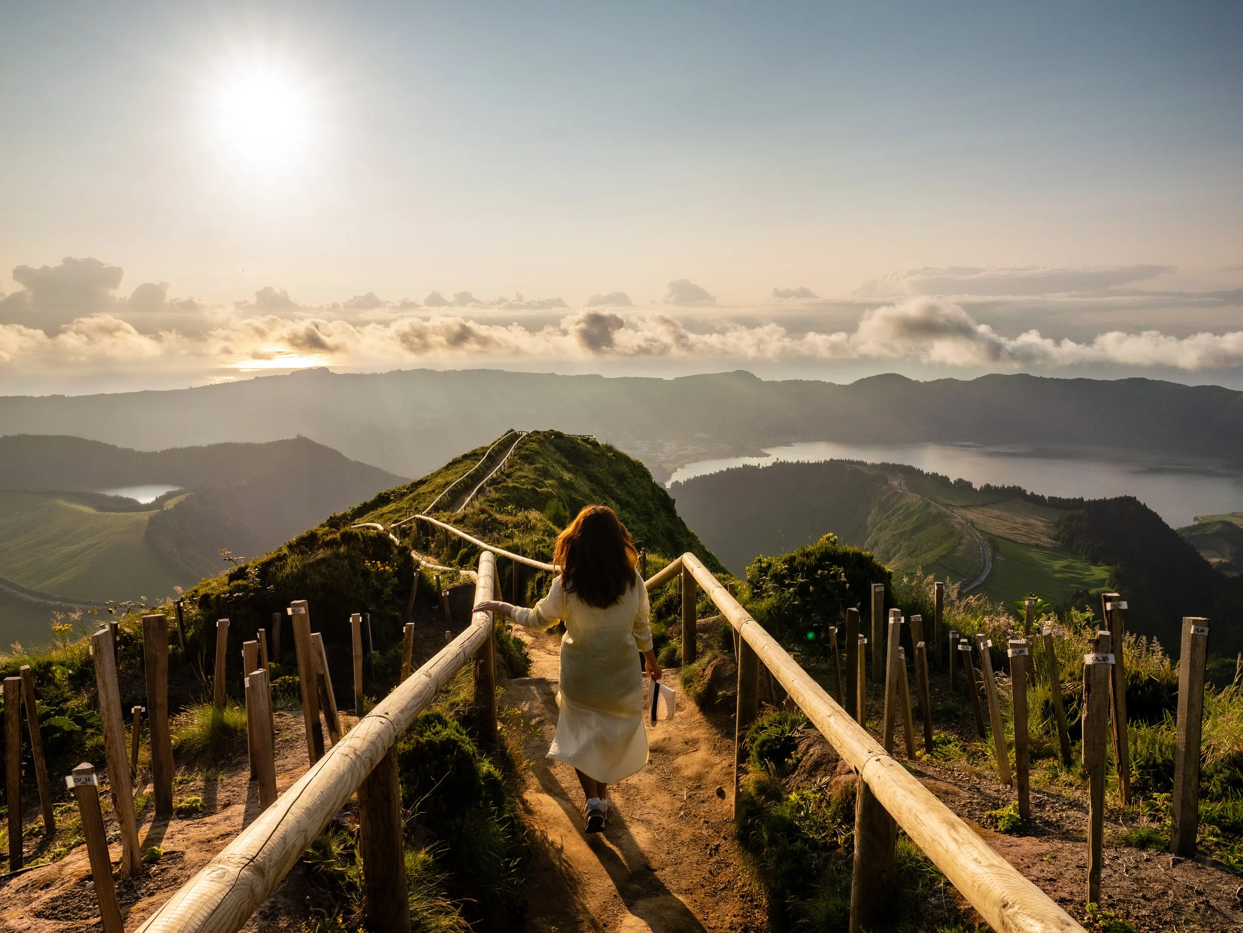 Traveler walking along a scenic viewpoint trail during a private tour in São Miguel, Azores, overlooking volcanic lakes and green landscapes
