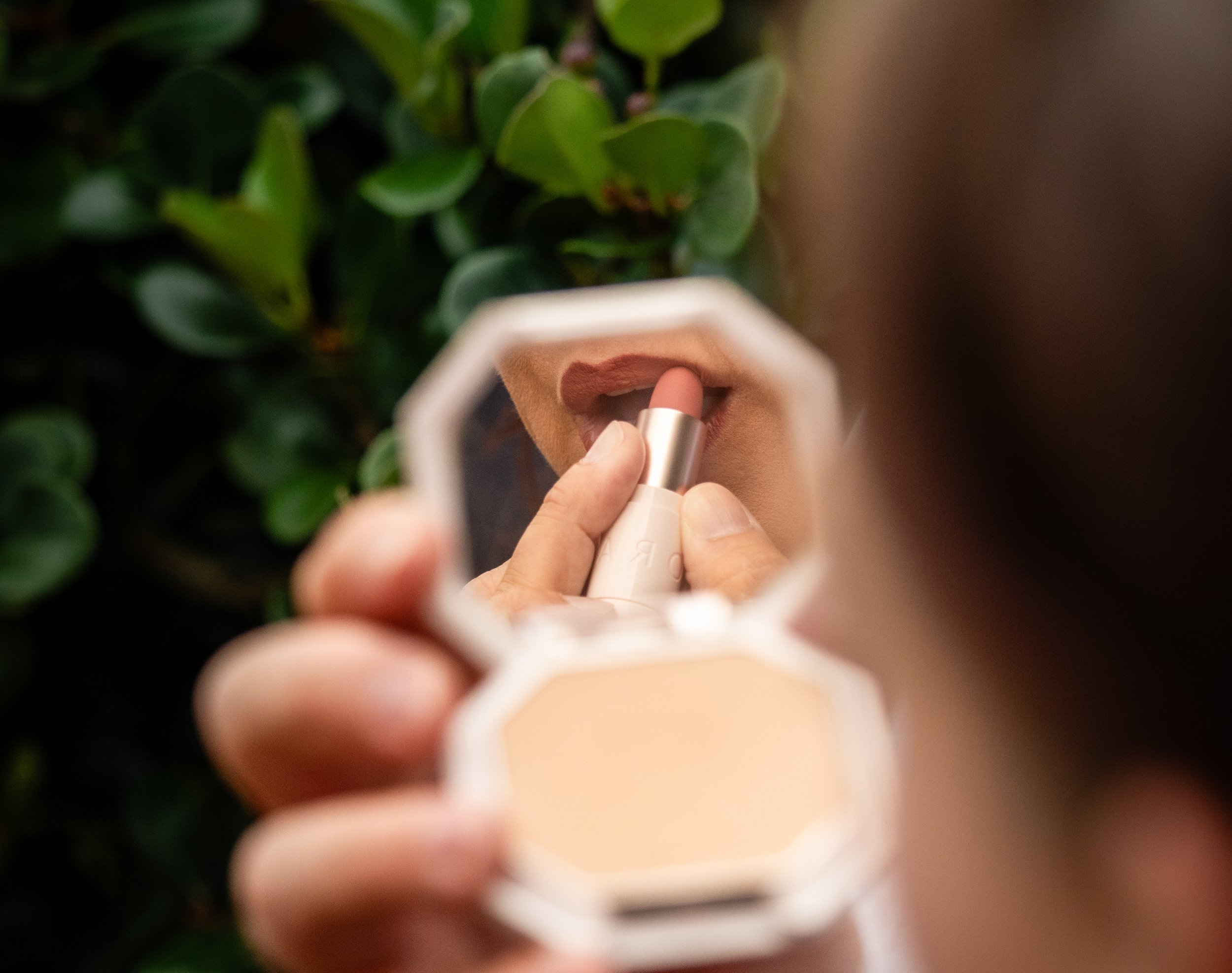 Applying lipstick before a photoshoot using a mirror as part of preparation