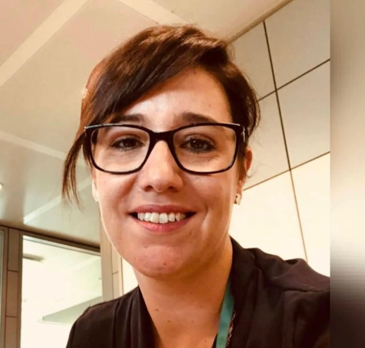 Person wearing glasses smiling in office setting.