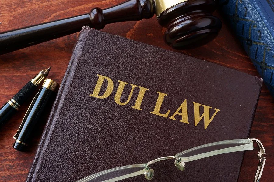 Close-up of a DUI Law book with gavel, pen, and eyeglasses symbolizing legal defense and drunk driving cases.