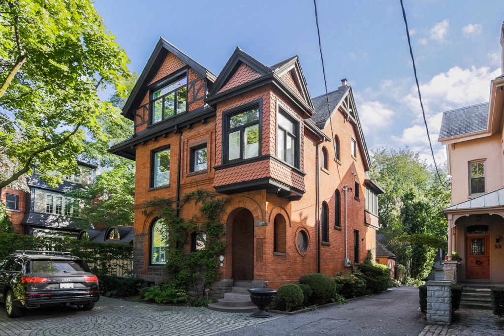 Three storey red brick house with a stone driveway