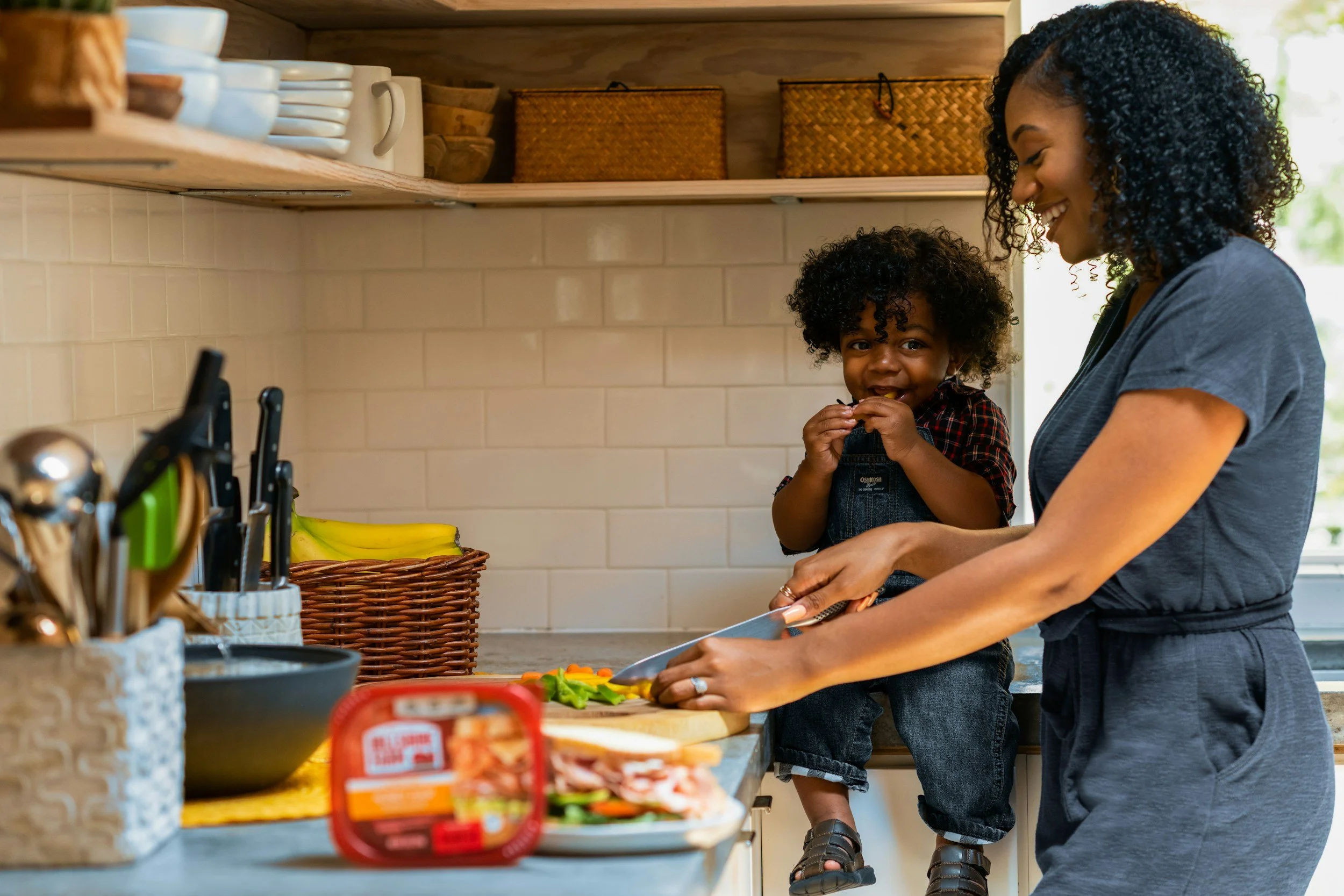 Happy mom and daughter in the kitchen making a yummy sandwhich