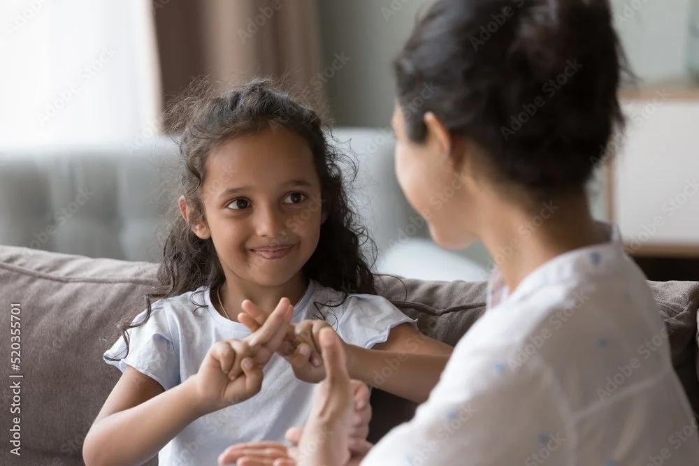 adult and child- child is crossing two fingers over her other two fingers like she is demonstrating a skill