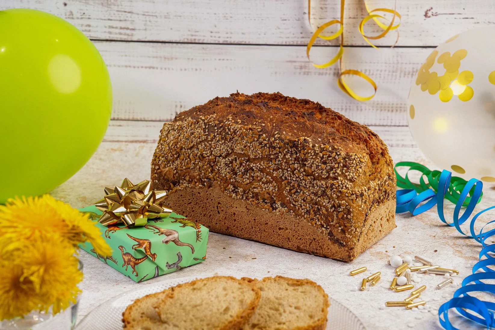 Leckeres Brot aus dem eigenen Backofen auf einem Tisch mit Luftballons und Geschenken