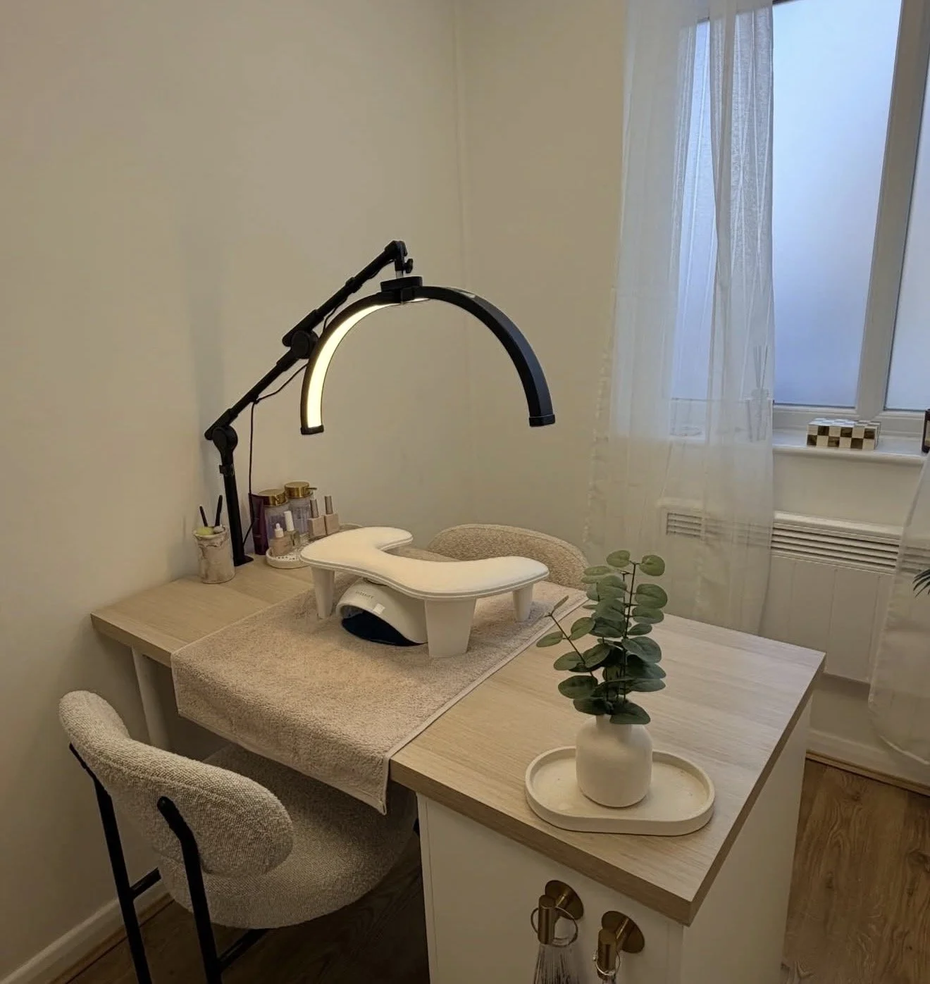 A room with a changing table, a lamp, and a small plant on a desk near a window.