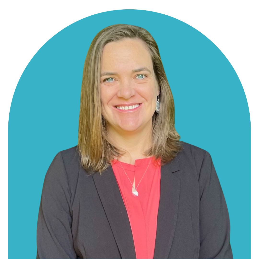 A professional woman with shoulder-length blonde hair, smiling, wearing a black blazer and coral blouse, with a necklace and earrings, against a blue background.