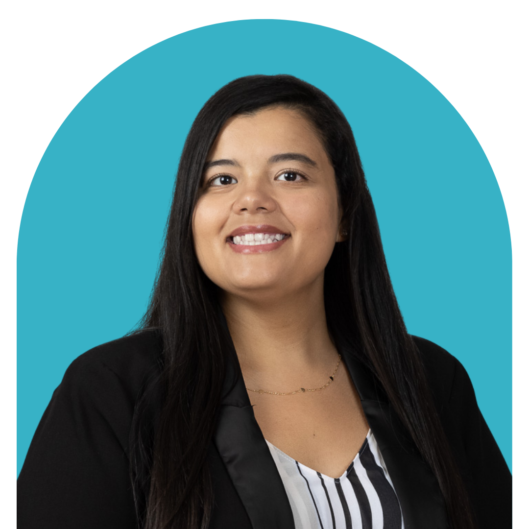 A woman with long black hair smiling, wearing a black blazer and a striped blouse, against a blue background.