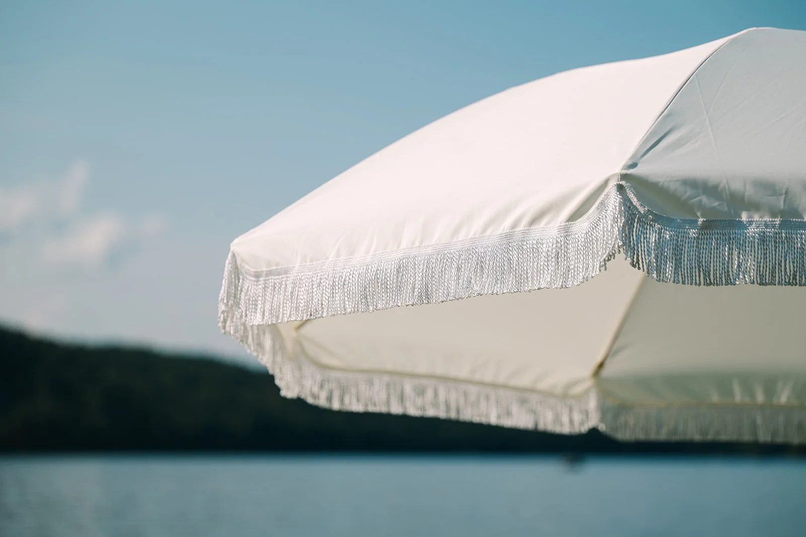 White fringe umbrella with base
Photo by Juniper Studios