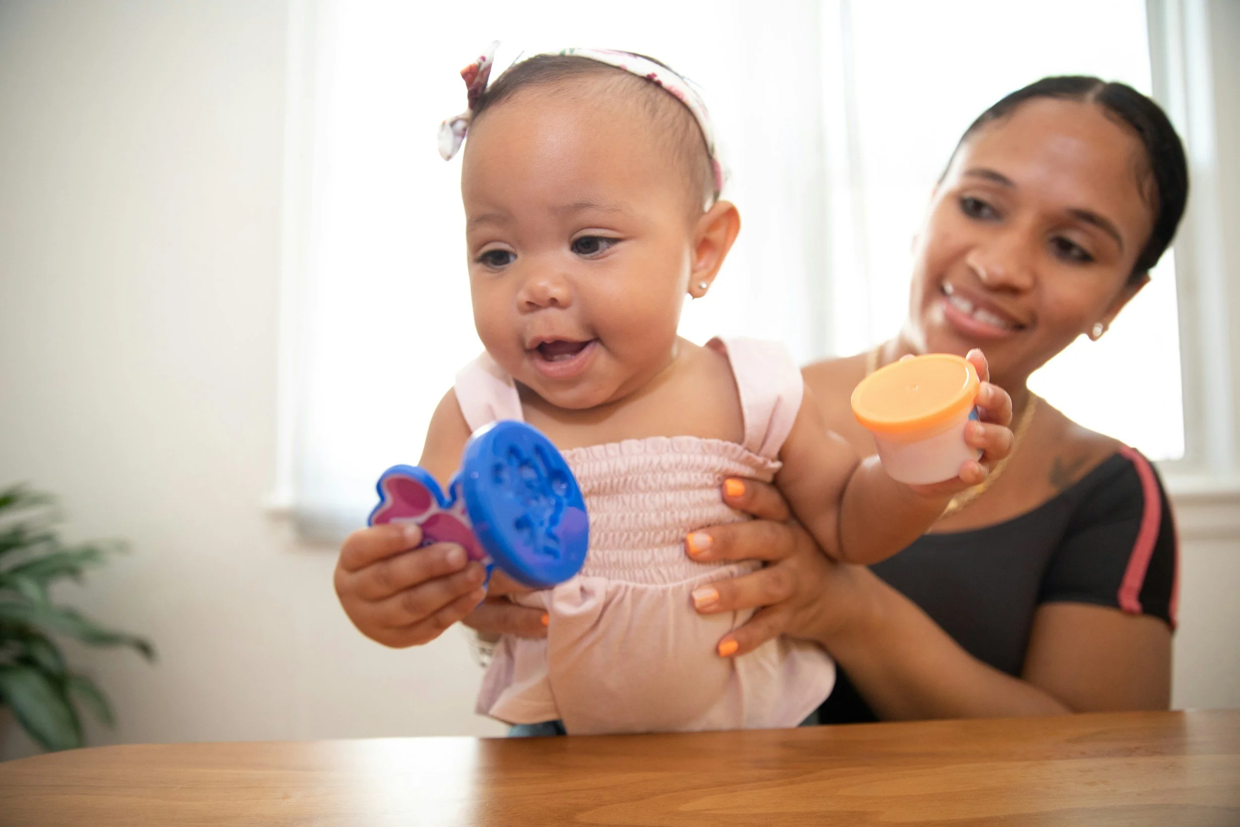 a child playing with toys while being held by their mom