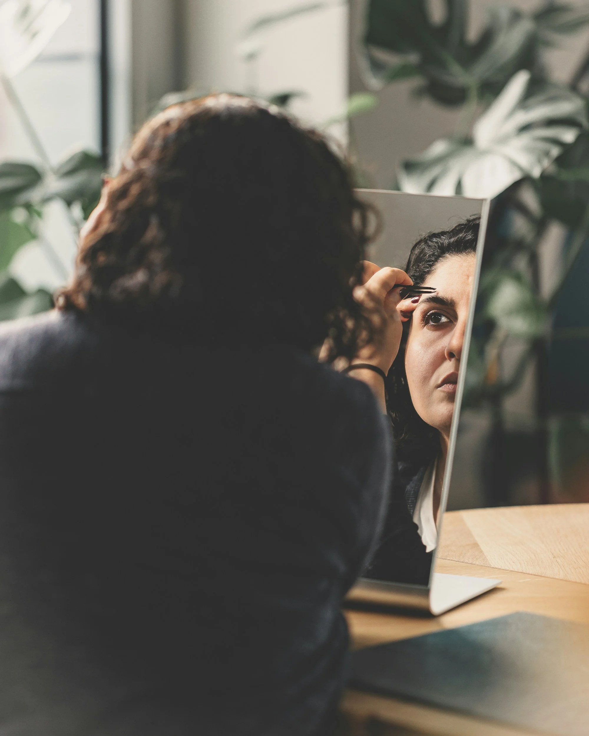 a person trimming their eyebrow in the mirror