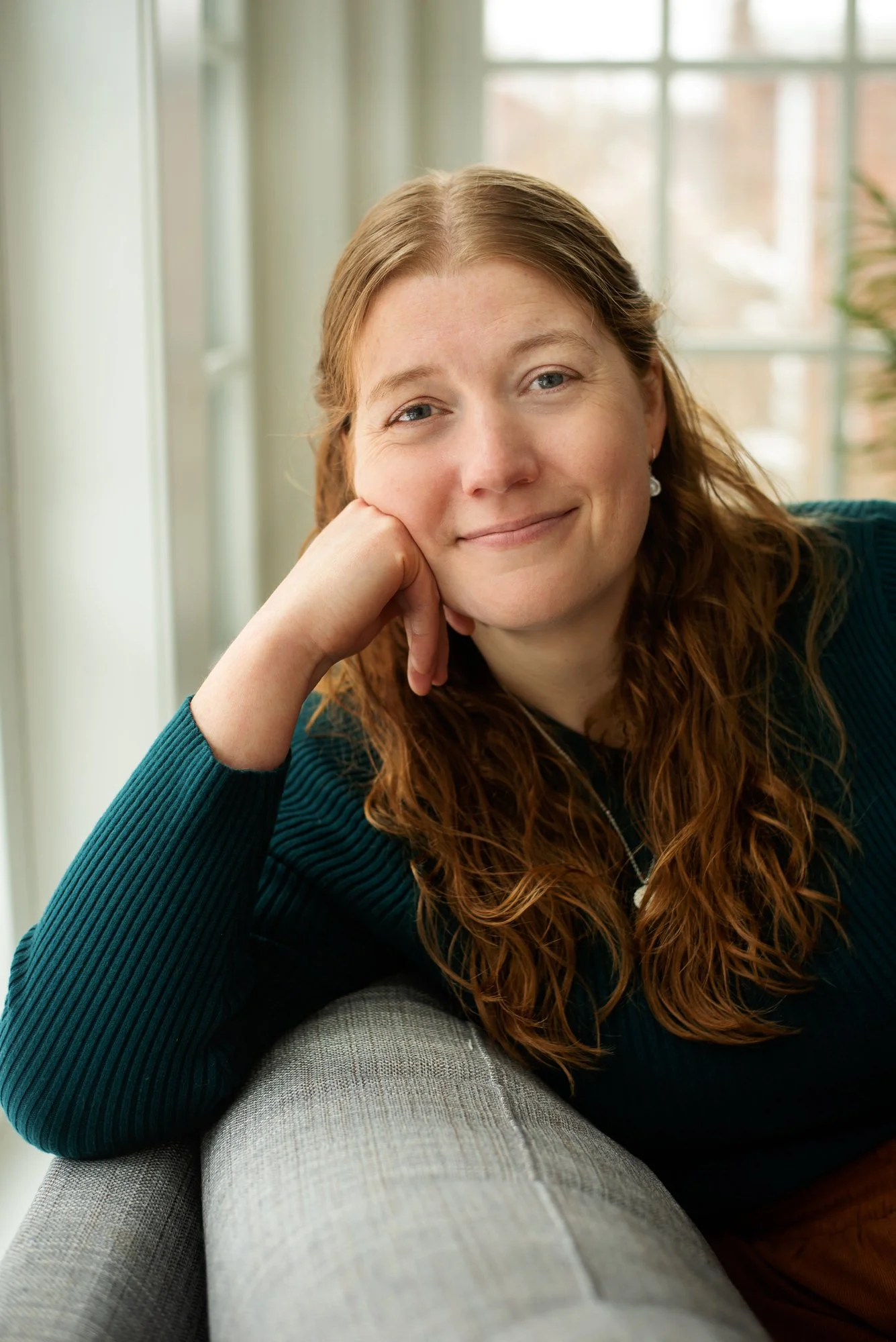 an image of Amie Anderson leaning on a couch smiling at the camera