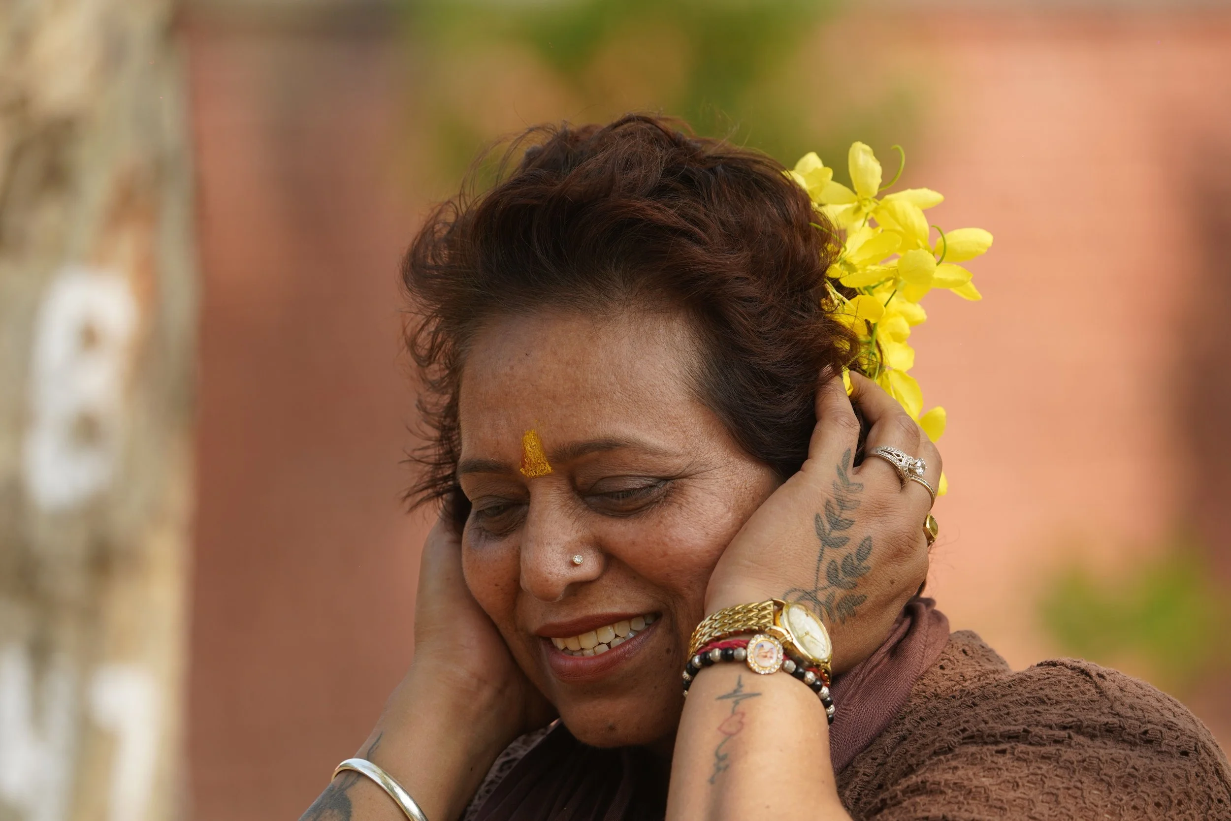 a woman cover her ears and smiling with flowers at the back of her head