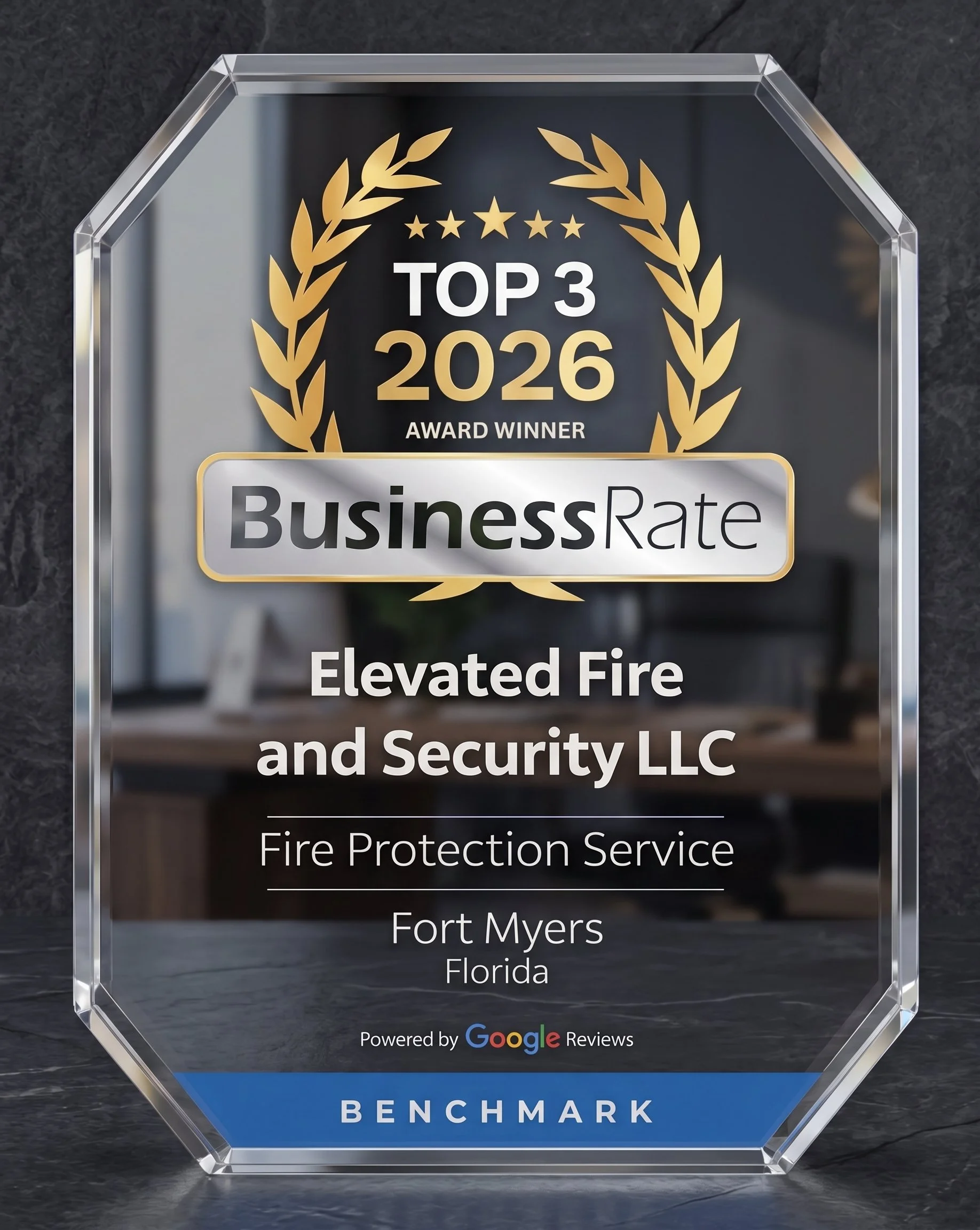 A clear crystal award with gold and black text that reads 'Top 3 2026 Award Winner,' awarded to 'Elevated Fire and Security LLC' in Fort Myers, Florida, by Benchmark, powered by Google Reviews.