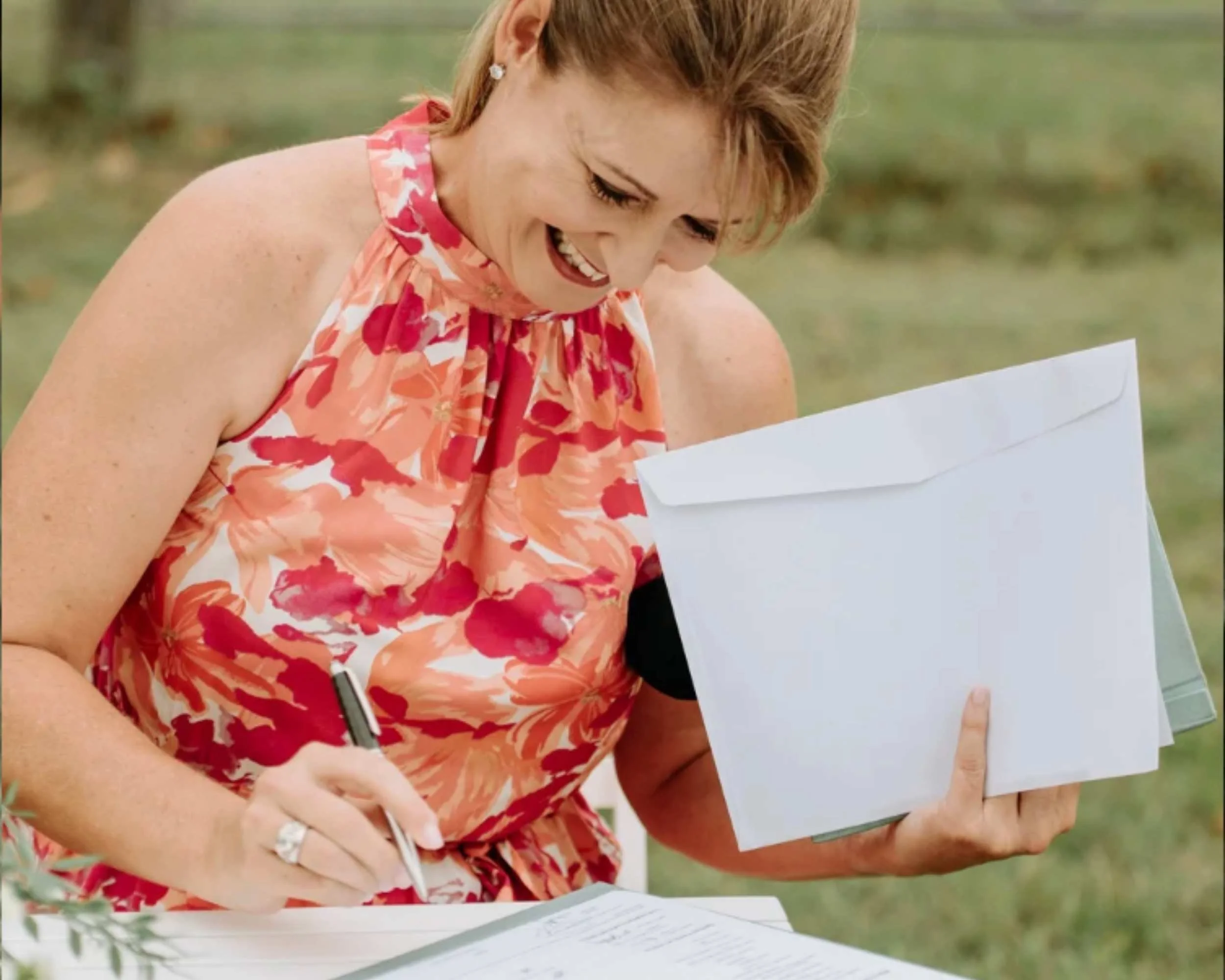 Woman in floral dress signing a document outdoors