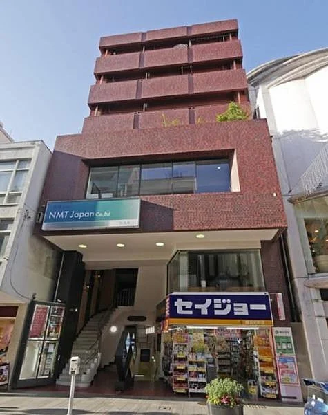 Multi-story building with a ground-floor convenience store and stairs leading to the upper floors, located in an urban area.