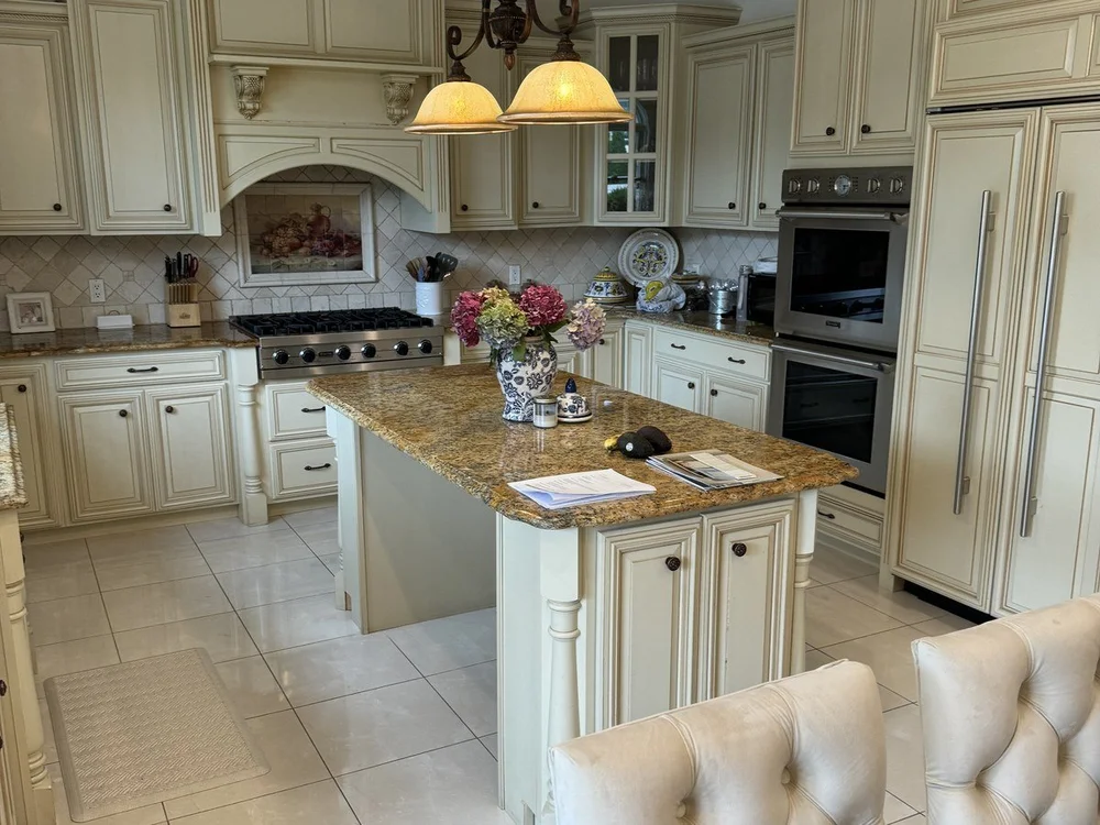 Before photo of the original Roslyn kitchen with cream cabinetry, granite island, chandelier, and enclosed layout