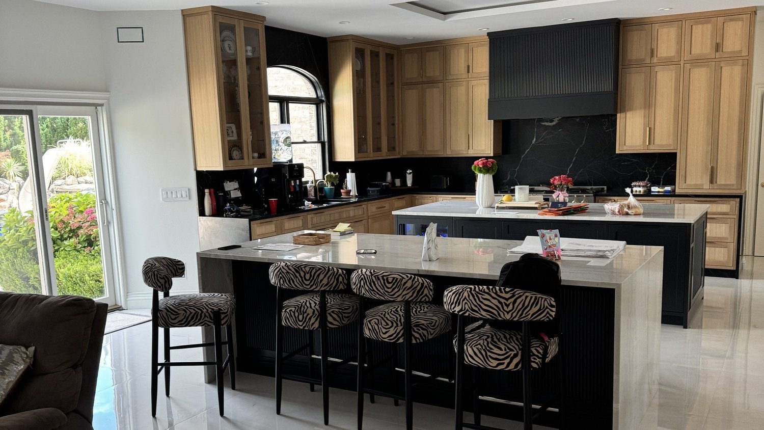 Completed Roslyn kitchen renovation with black island, wood cabinetry, black stone cooking wall, and marble-look counters