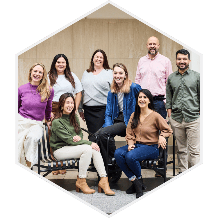 Group of eight diverse people smiling and posing together in an indoor setting.
