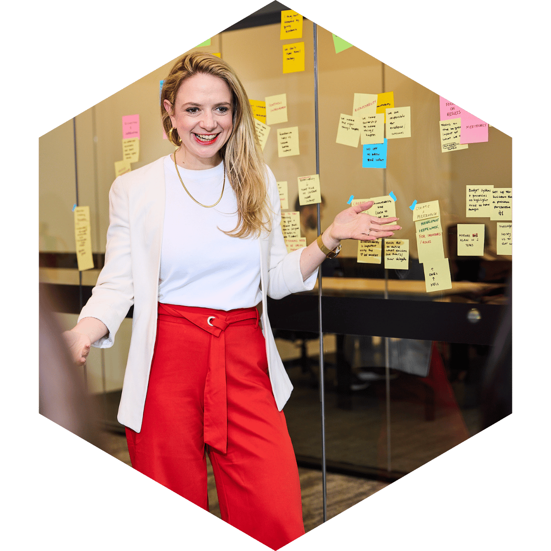 A woman presenting in front of a wall with sticky notes during a meeting or workshop.