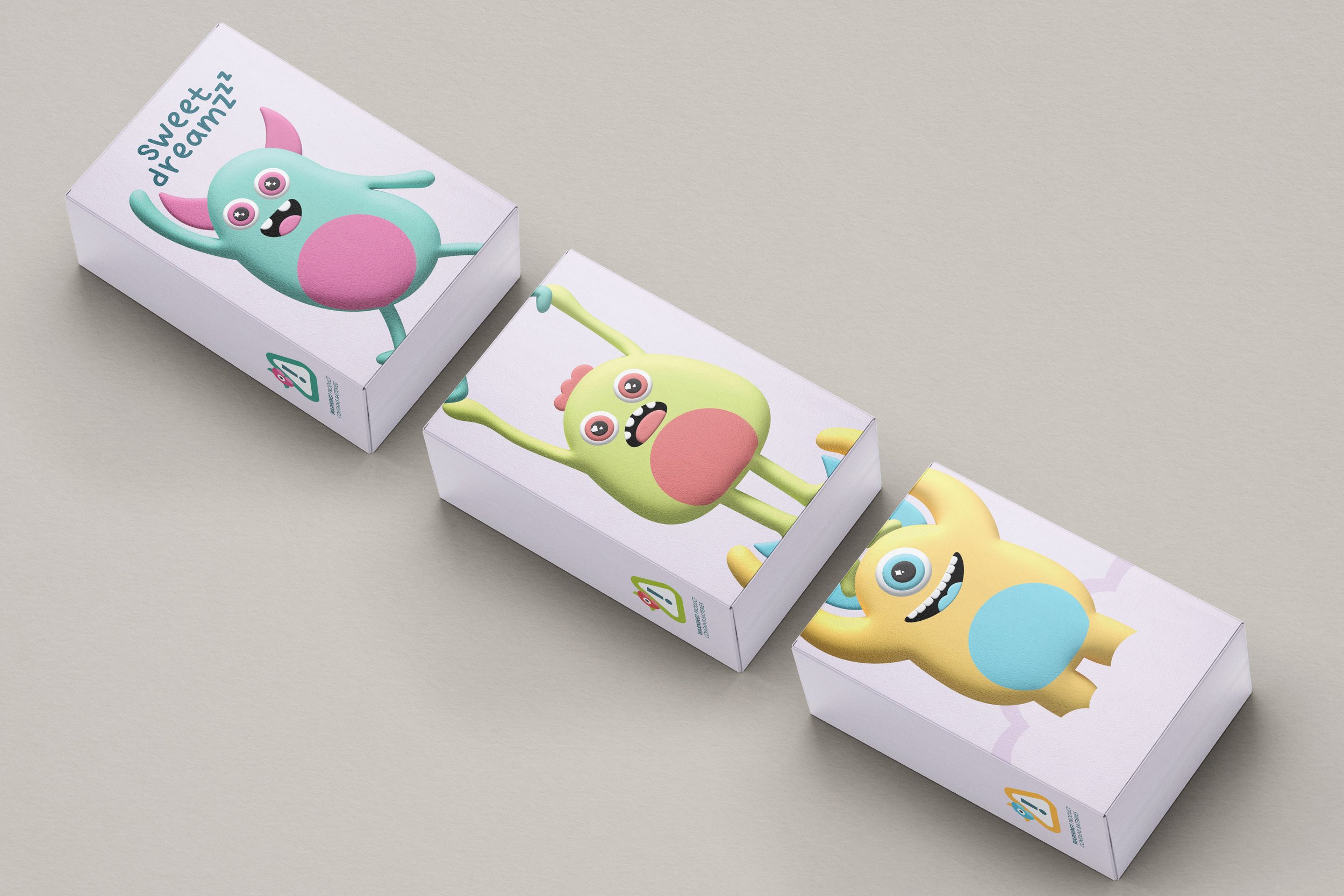 Colorful boxes featuring cartoon monster characters with large eyes and open mouths, placed on a light gray surface.