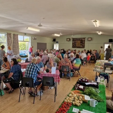 People sitting at tables during the Saturday Market at Walkhampton Memorial Hall