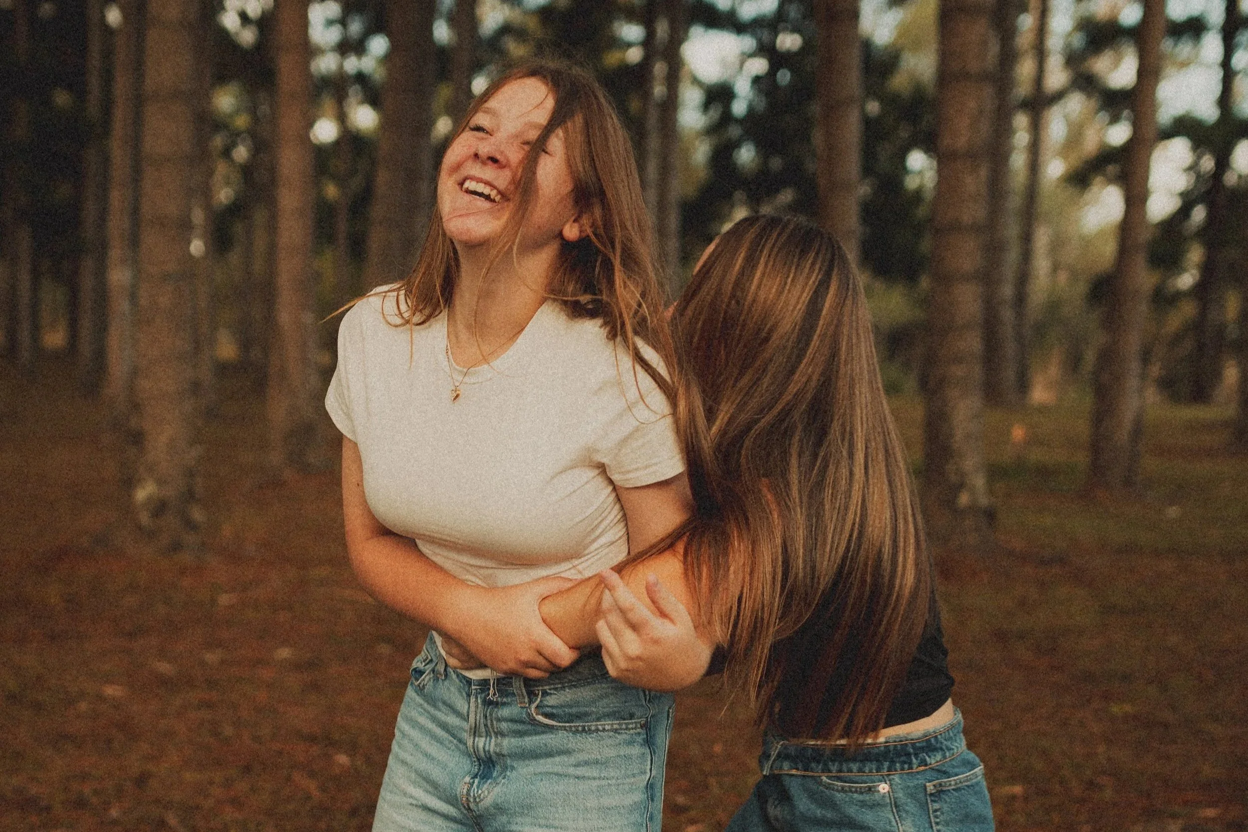 A family of four, including a man, woman, and two babies, sharing a warm hug and cuddling on a bed.