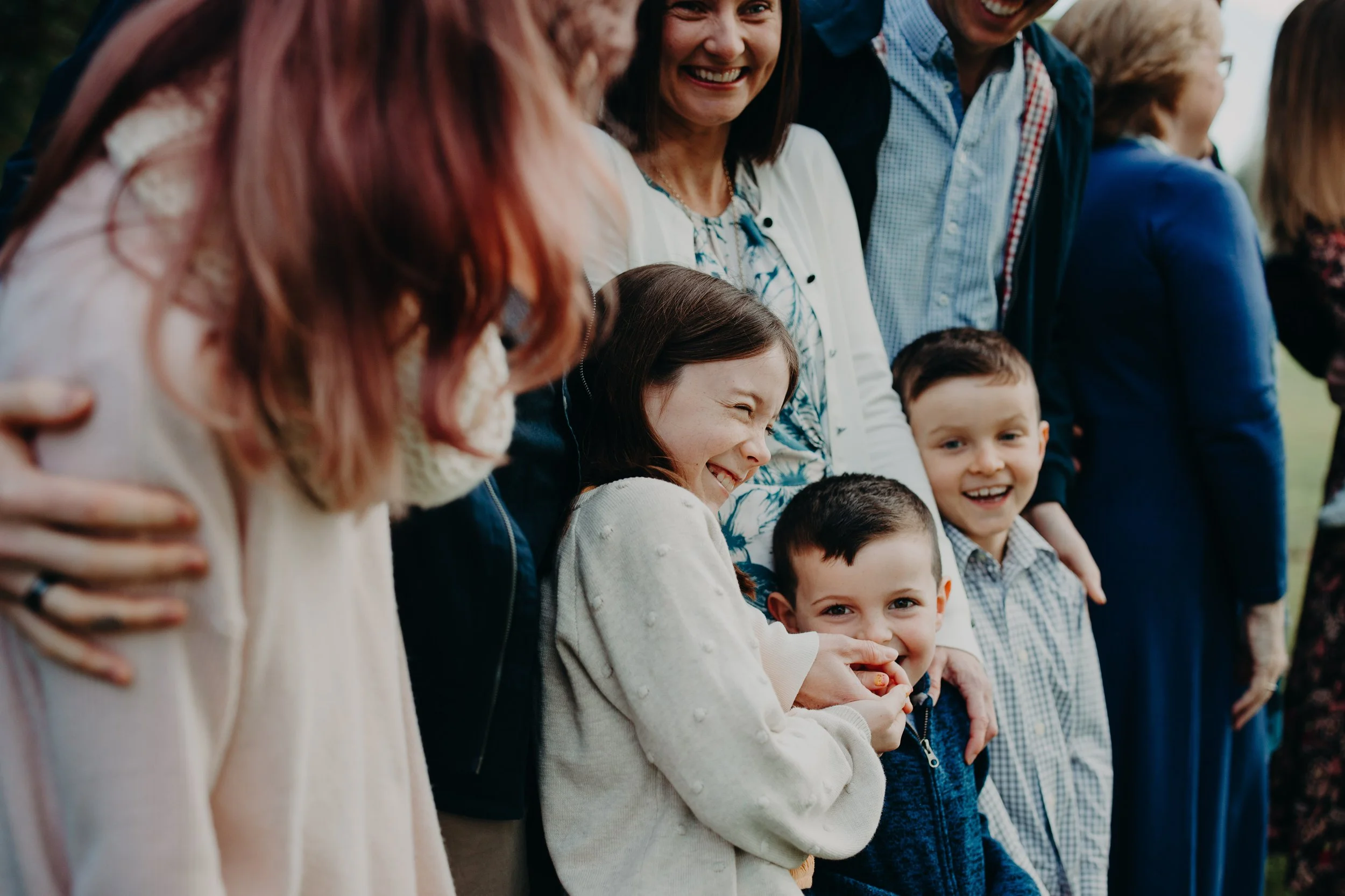 Group of people smiling and posing for a photo outdoors, including children and adults
