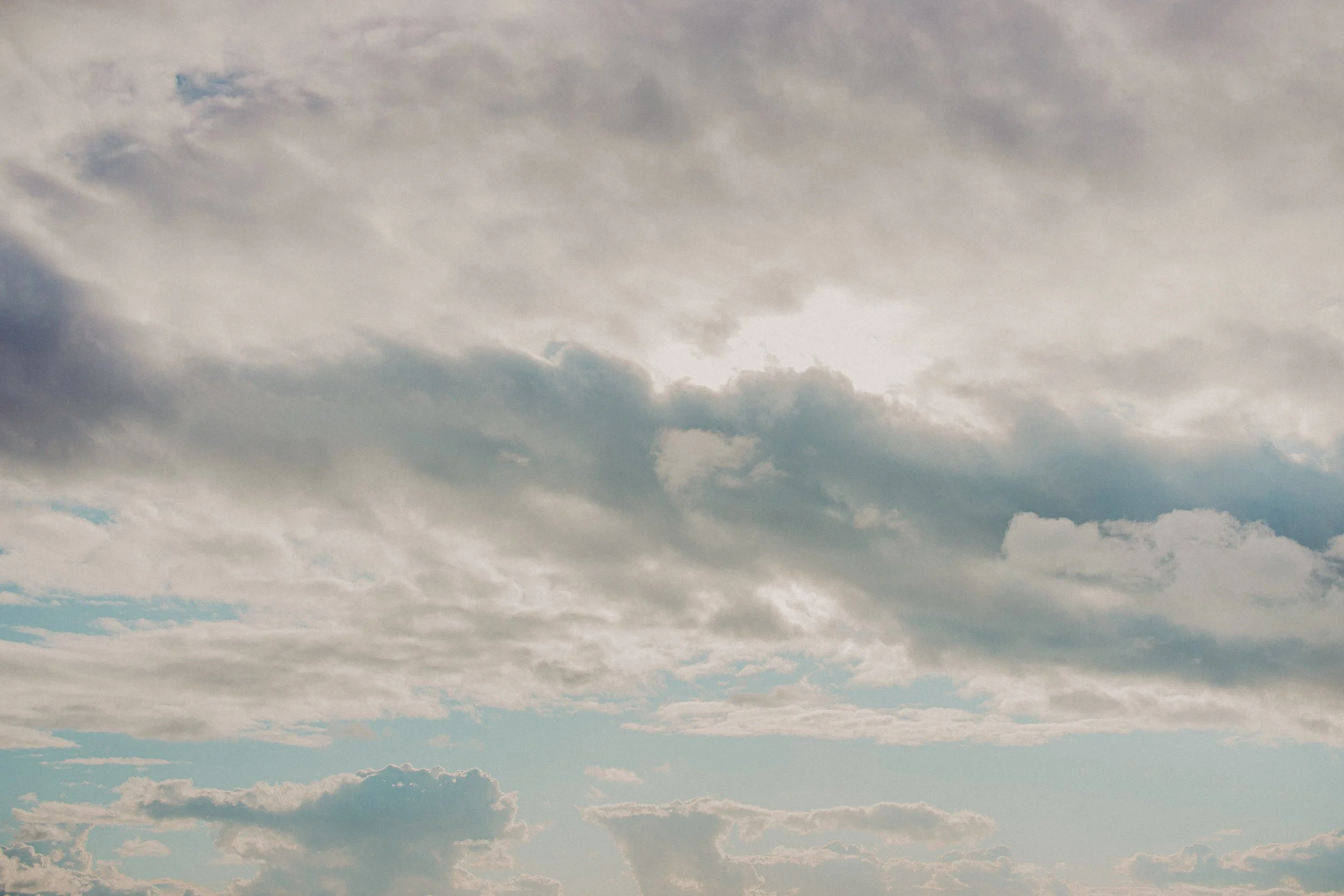 Cloudy sky with patches of blue and sunlight peeking through the clouds.